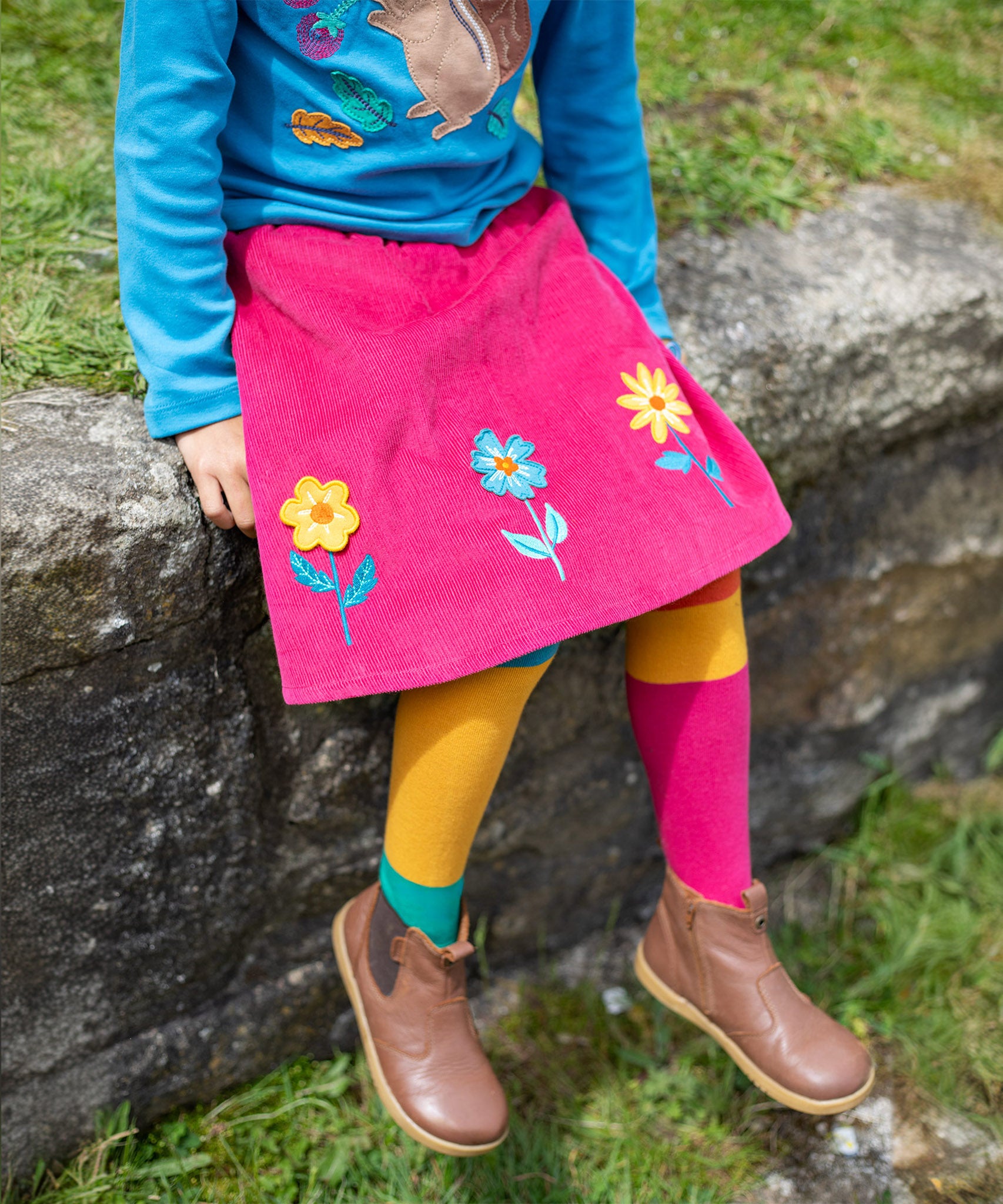 A child wearing the Frugi Norah Tights - Deep Water Colour Block with a Frugi skirt and top