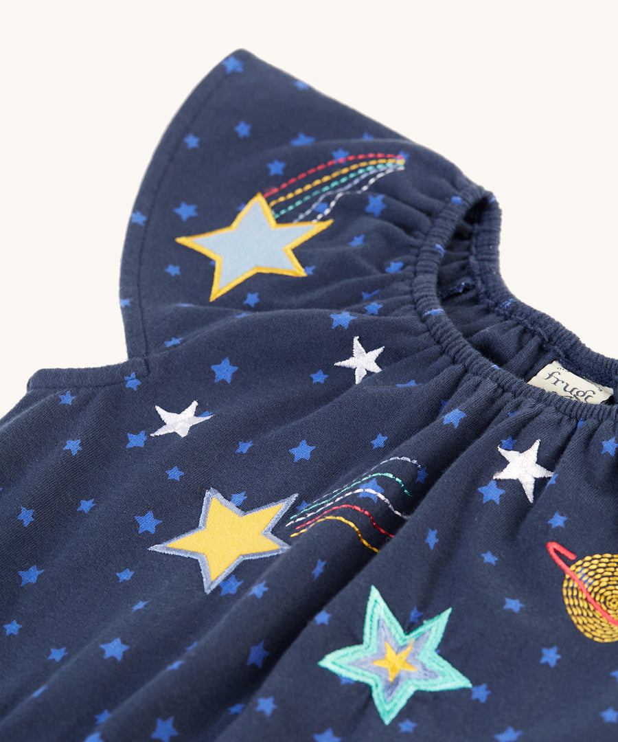 A closer look at the adorable capped sleeves on the Frugi Lorena Jumpsuit - Starry Night/Space. Also shown are the colourful, embroidered and printed stars on the top part of the chest, on the jumpsuit