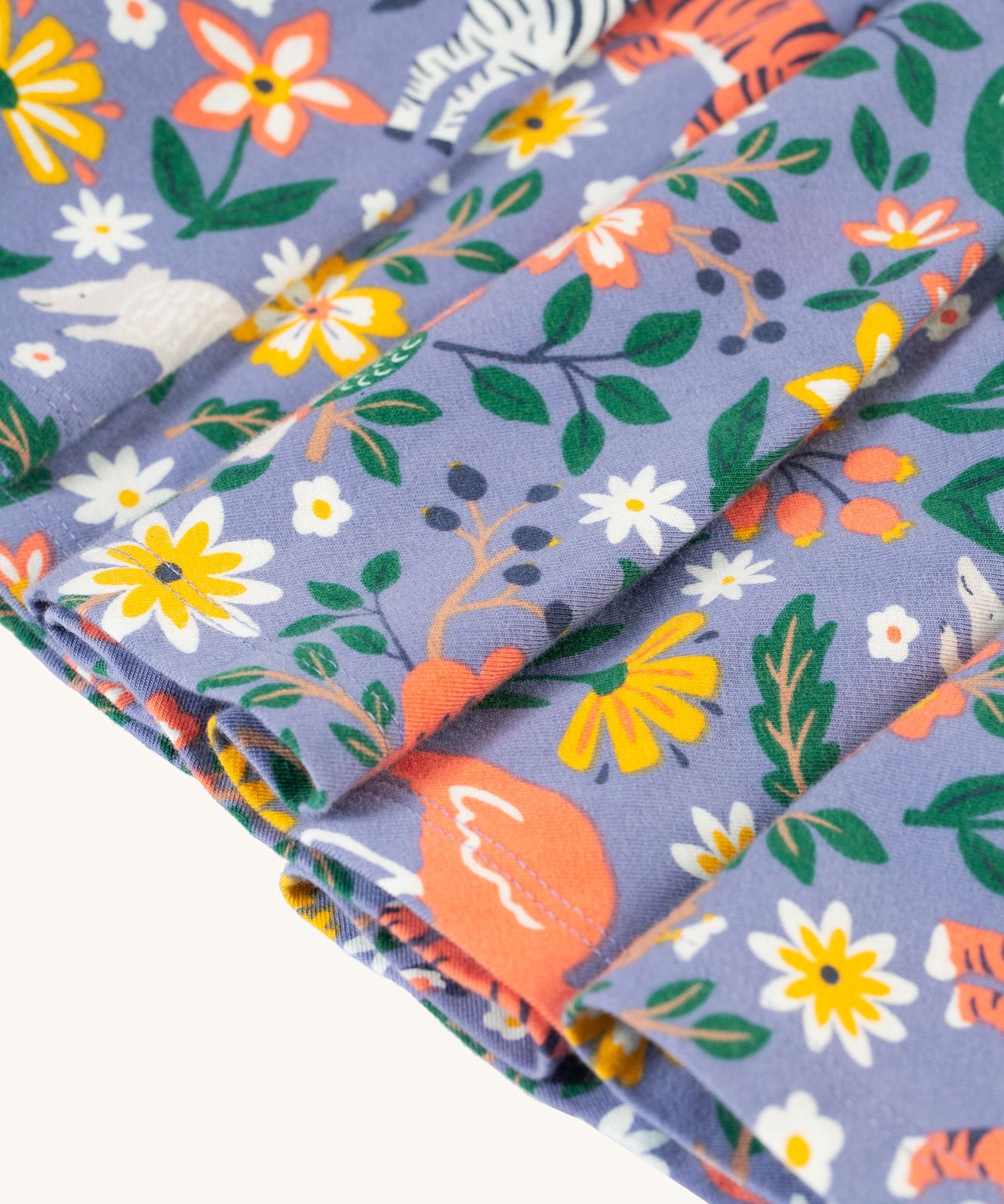 A closer view of the twirly skirt fabric on the Frugi Sofia Skater Dress - Rainforest Friends, which shows the animal and flower/leaf wildlife print