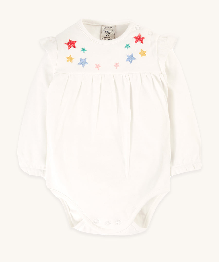 Frugi Eviana Baby Body - Soft White/Stars. A white bodysuit with soft frill cuff gathers and a pretty shoulder frill, with embroidered little stars on the front panel. With popper fastenings at the side of the neck and between the legs.