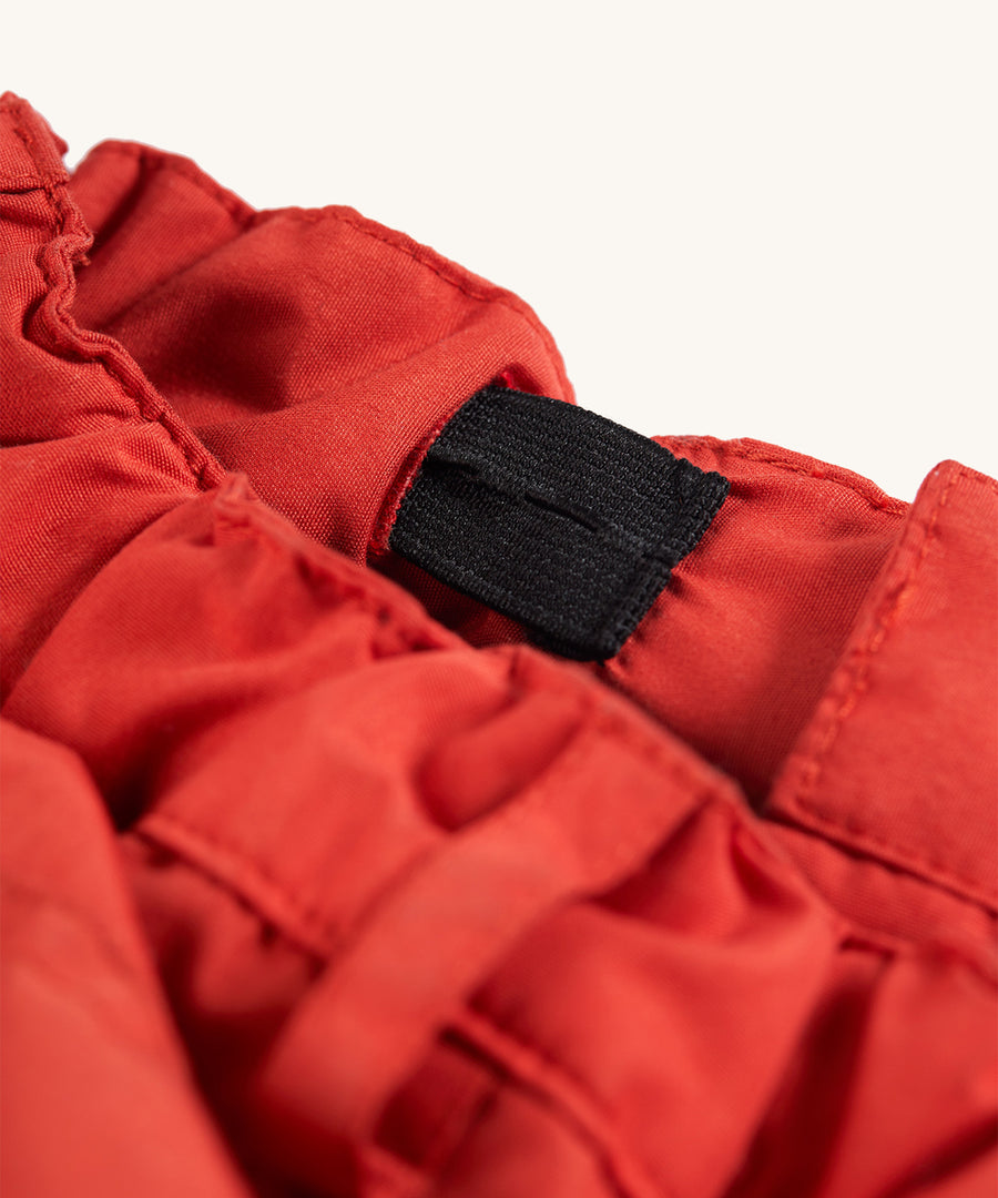 Waistband detail on the Frugi Expedition Trousers - Paprika / Indigo on a plain background.