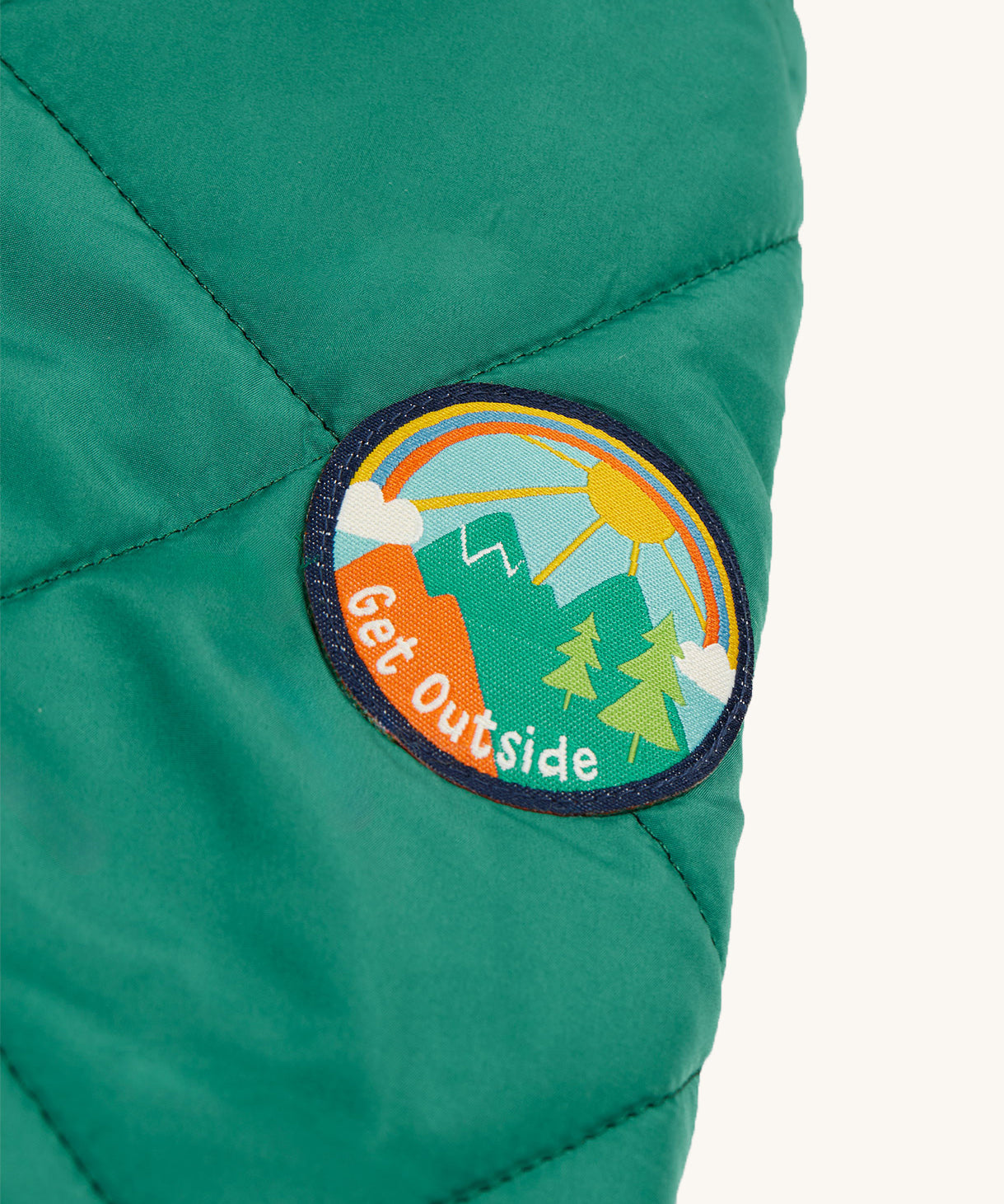 The Get Outside patch on sleeve of the Frugi Robin Reversible Quilted Jacket - Teal/Moon