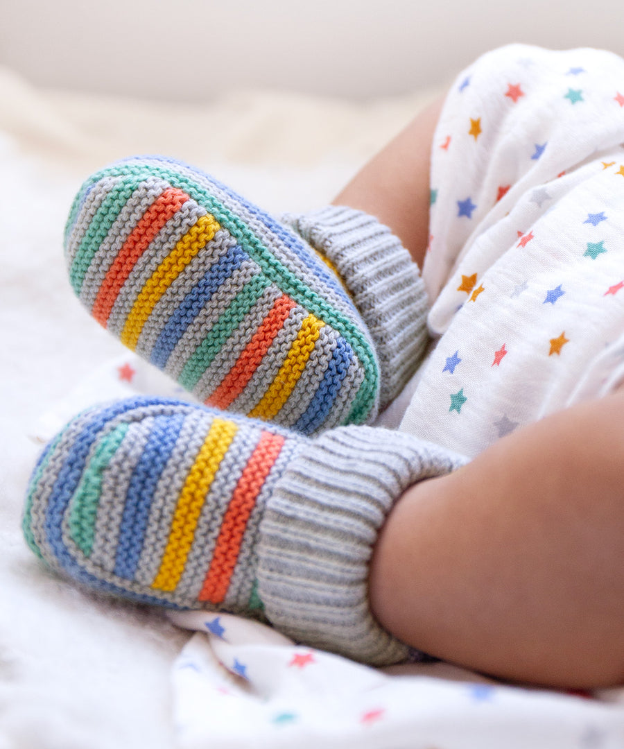 A closer look at the Frugi Briar Knitted Booties - Grey Marl Stripe, being worn by a baby