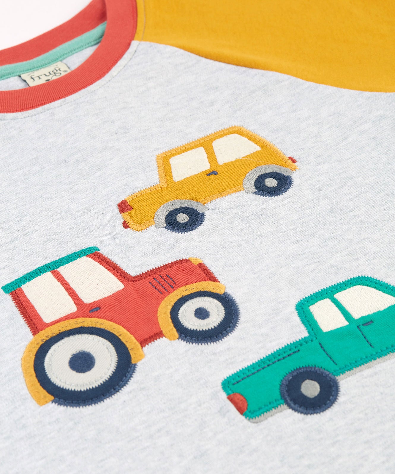 A look at the fun vehicle appliques on the front of the Frugi Alfie Raglan Top - Grey Marl/Vehicles