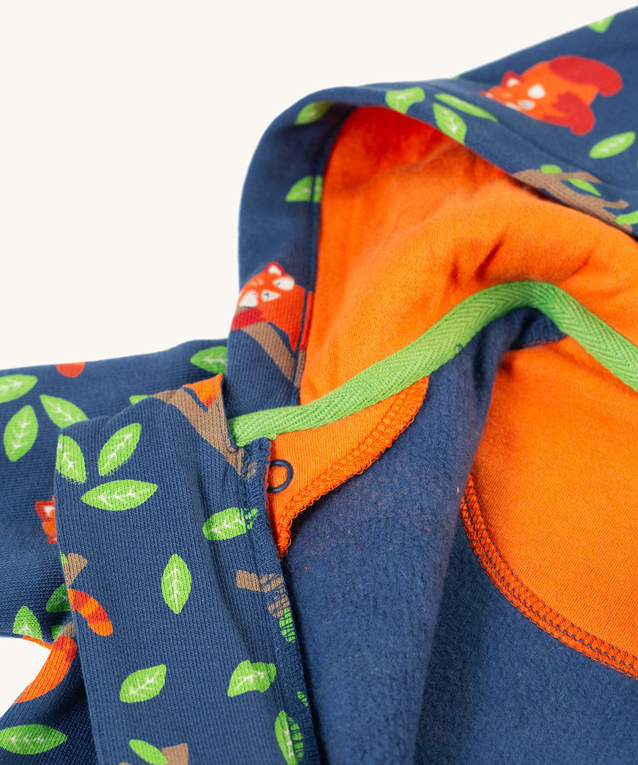 A closer look at the hood on the Frugi Snuggle Suit - Red Panda Pals. The image shows the inside of the hood with an orange lining and the red panda pattern on the front and sleeves of the snuggle suit