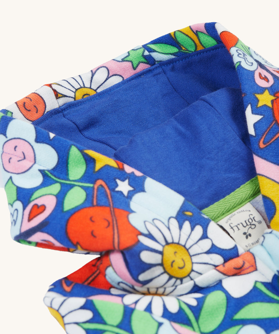 The hood on the Frugi Snuggle Suit - Retro Happy, with a royal blue hood lining and the retro happy print on the outside 