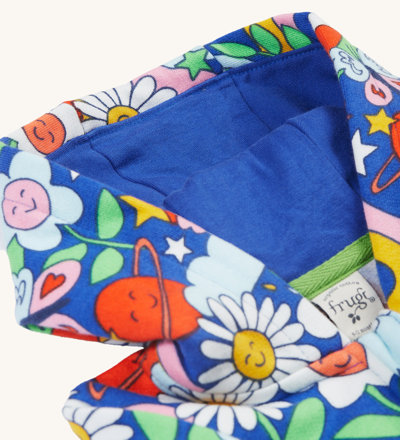 The hood on the Frugi Snuggle Suit - Retro Happy, with a royal blue hood lining and the retro happy print on the outside 