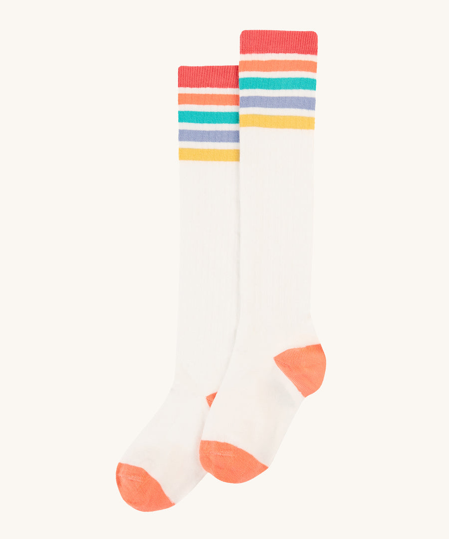 Frugi Hygge Rib Knee Socks - Soft White Rainbow. Knee length socks in white, with rainbow stripes at the top in red, orange, green, blue and yellow. With orange toes and heels