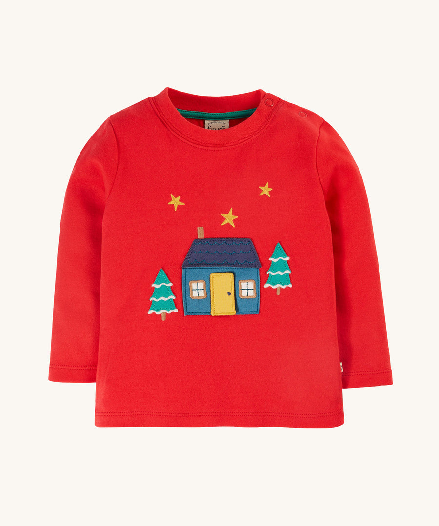 Frugi Ira Interactive Applique Top - True Red/Winter Cottage. A lovely, long sleeve, organic cotton, festive jumper in red. With a cosy home, gold star and snowy tree applique detail