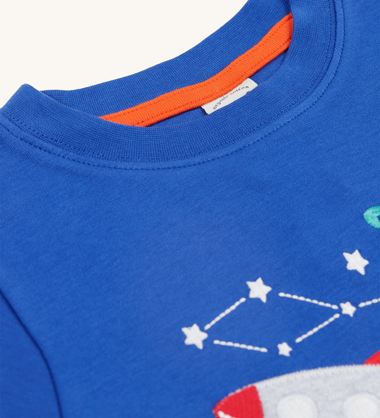 A closer look at the collar on the Frugi Little Creature Applique Top - Blue Tang/Rocket. Part of the space/rocket applique is showing at the bottom right of the image