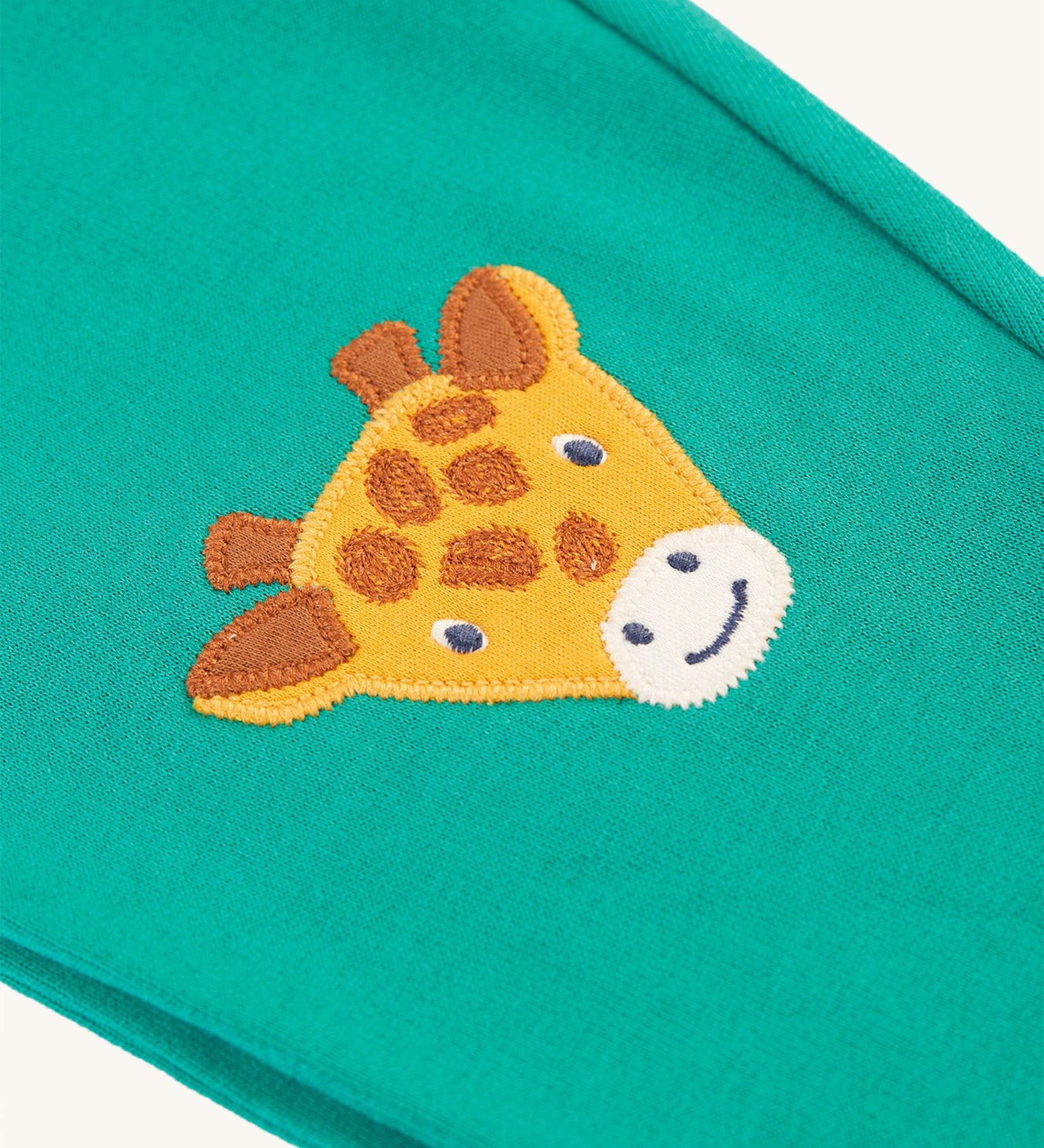 A closer look at the giraffe patch on the Frugi Character Crawlers - Iguana/Tiger