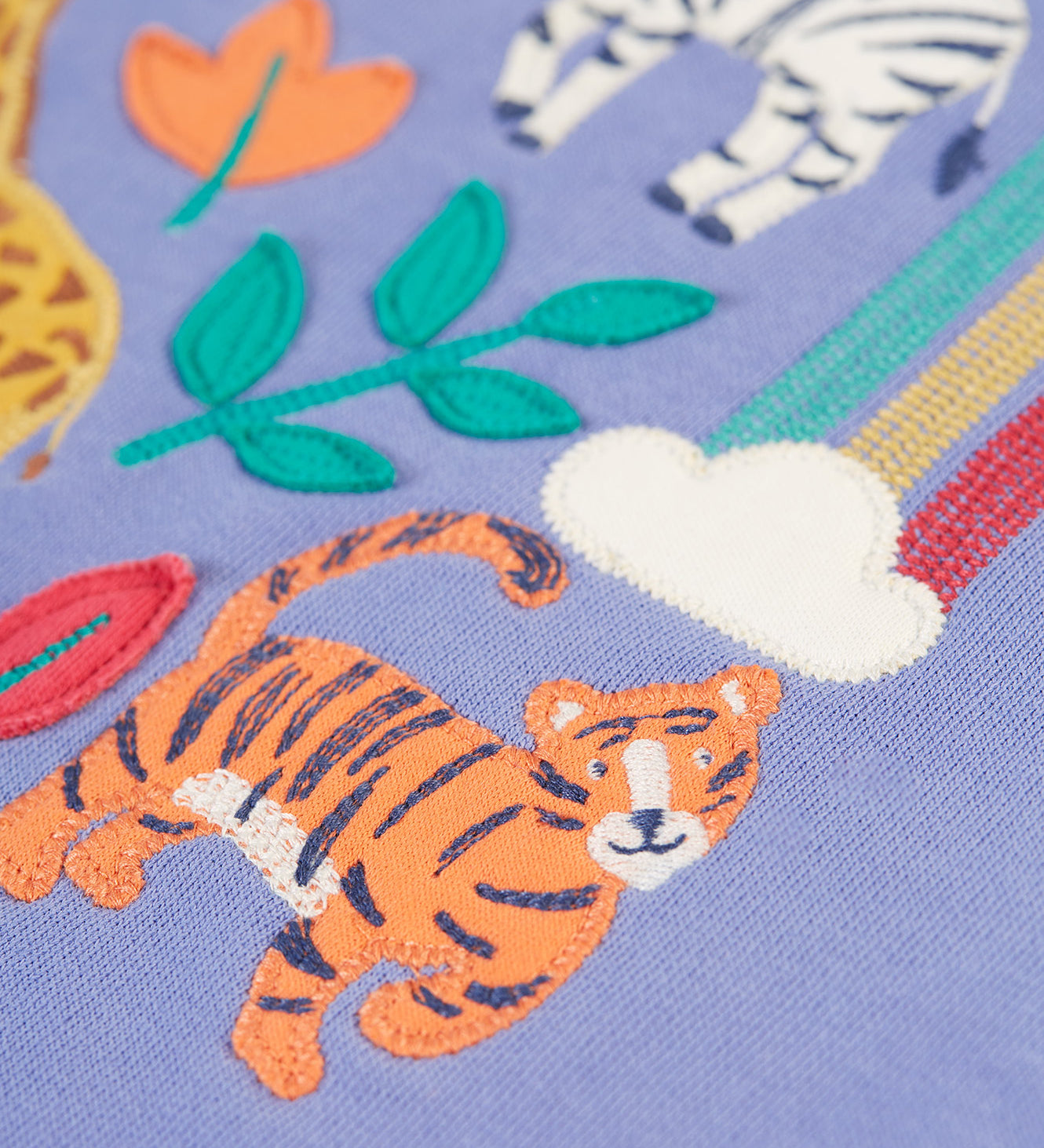 A closer look at the tiger applique with embroidered details, on the Frugi Ria Hoodie Dress - Grape/Stay Wild. Also shown is a small cloud with the start of the rainbow, applique leaves and the legs of the zebra