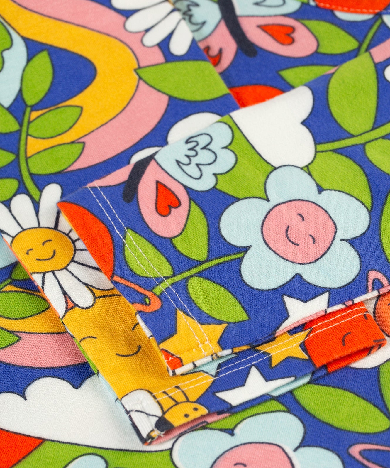 A closer look at the bottom of the sleeves in the Retro Happy print, folded across the Frugi Sofia Skater Dress - Retro Happy