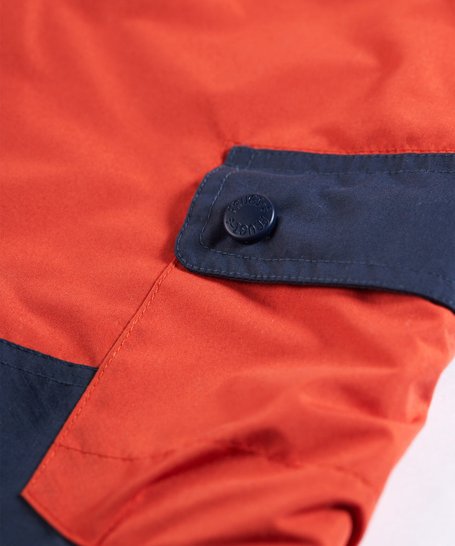 Pocket detail on the Frugi Expedition Trousers - Paprika / Indigo on a plain background.