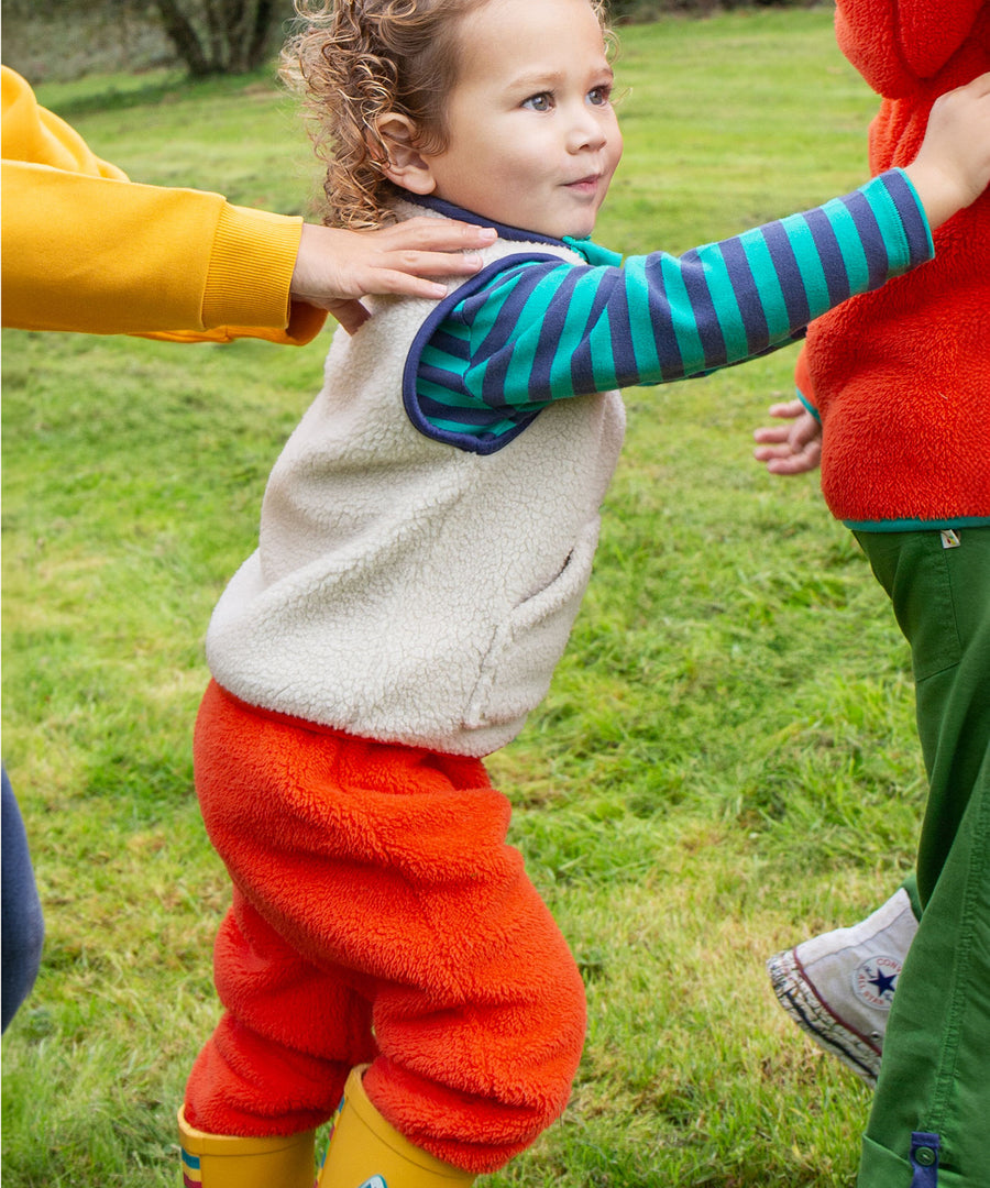 A child happily playing with others, whilst wearing Frugi Ted Fleece Pull Ups - Bonfire