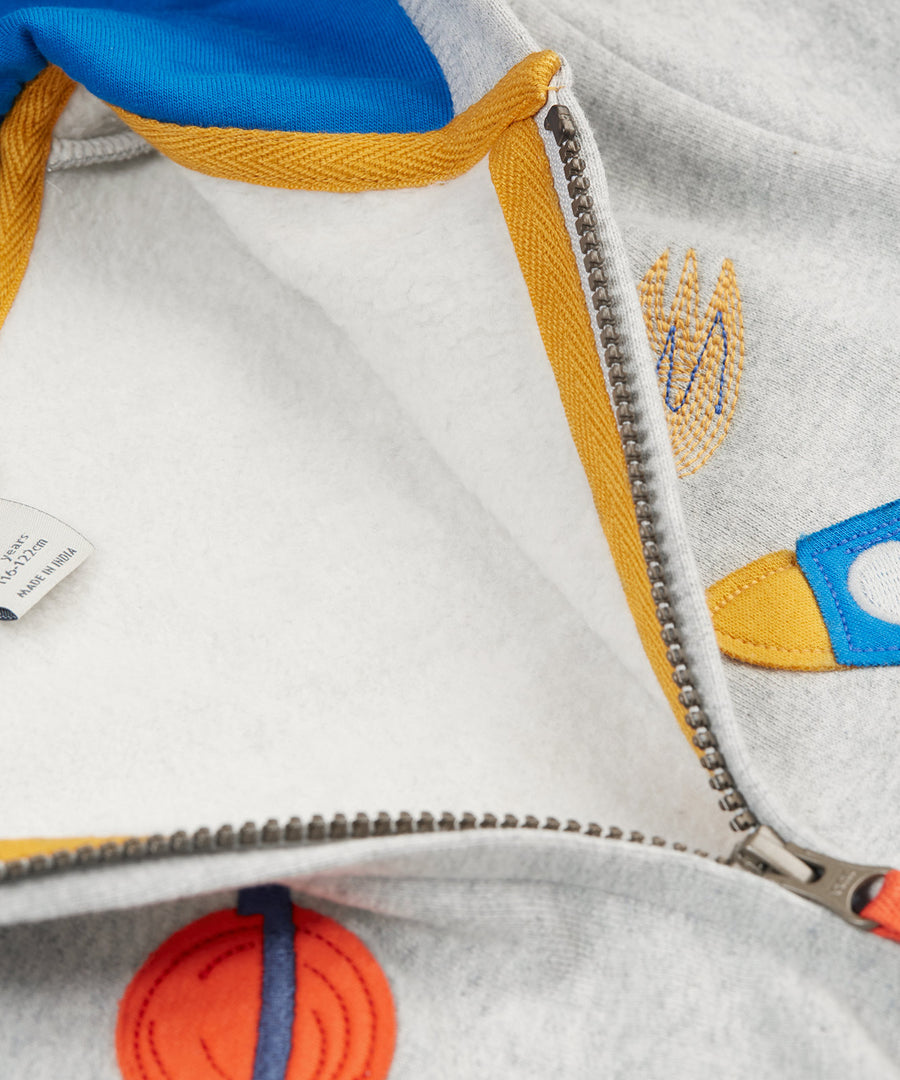 A closer look at the open zip on the Frugi Carbis Zip Hoodie - Grey Marl/Rocket. The orange planet and rocket applique are partly showing