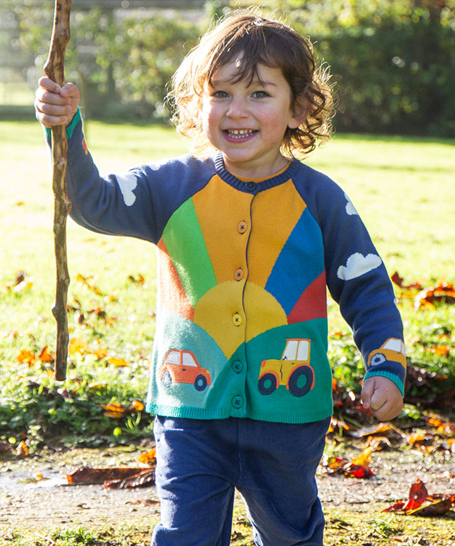 A child playing outside, wearing the Frugi Reva Applique Cardigan - Navy Blue/Sunrise