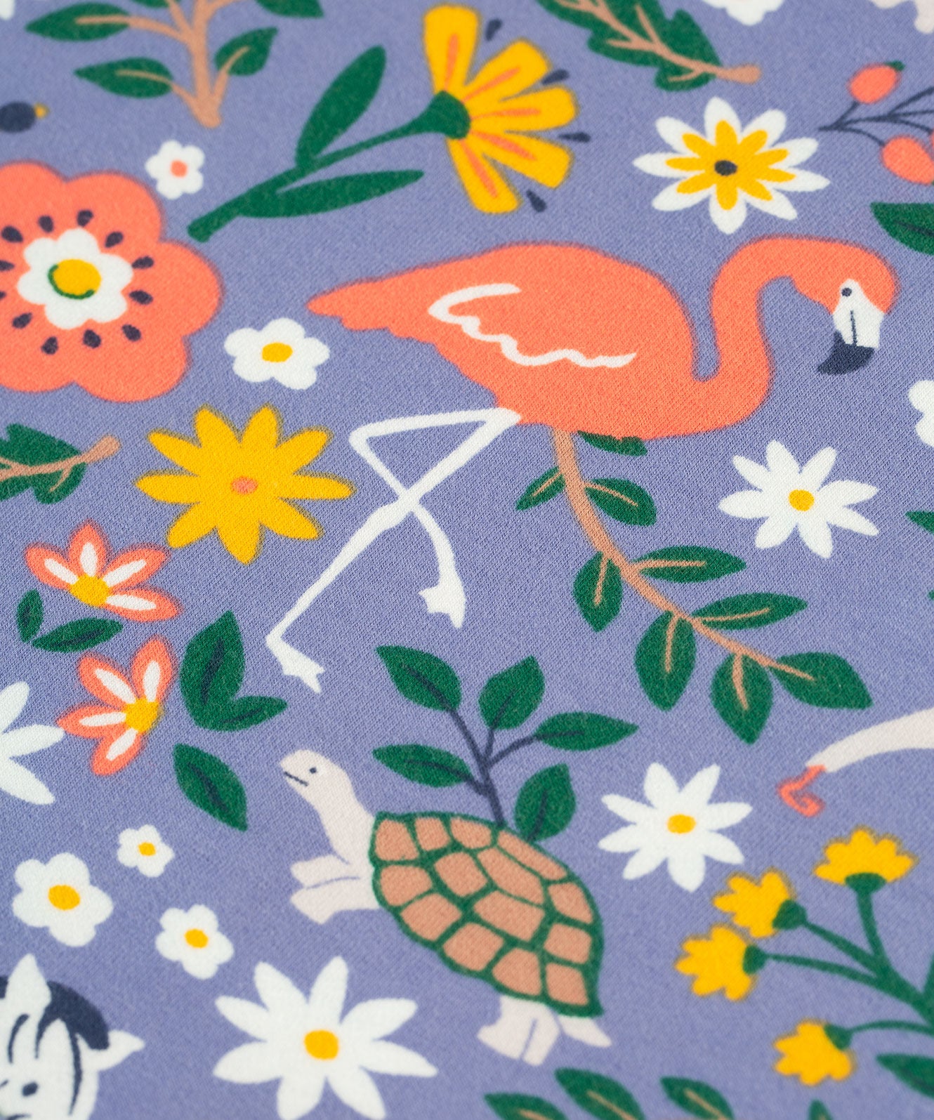 A closer look at the animal and plant/leaf print on the Frugi Sofia Skater Dress - Rainforest Friends. The image shows a flamingo stood on one leg, a turtle, the top of a zebra, and colourful flower and leaves