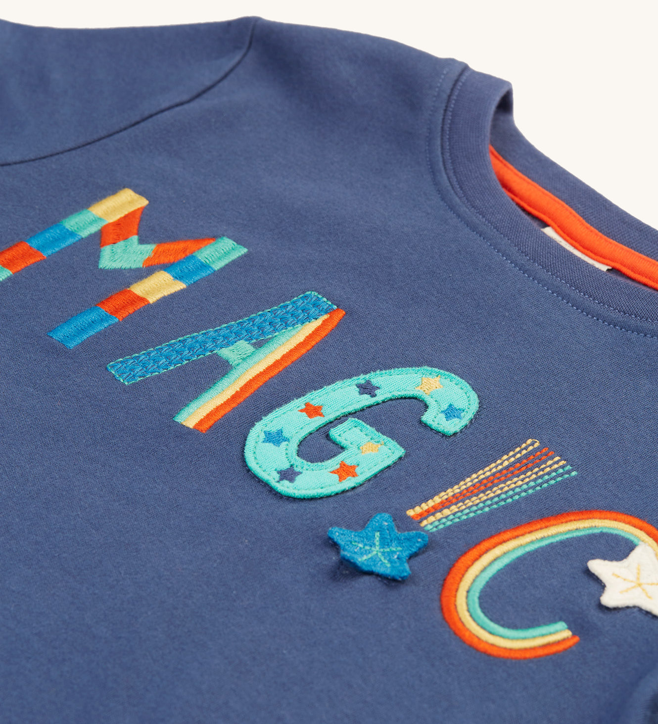 A closer look at the colourful, rainbow embroidered and applique magic lettering on the Frugi Adventure Applique Top - Navy Blue/Magic