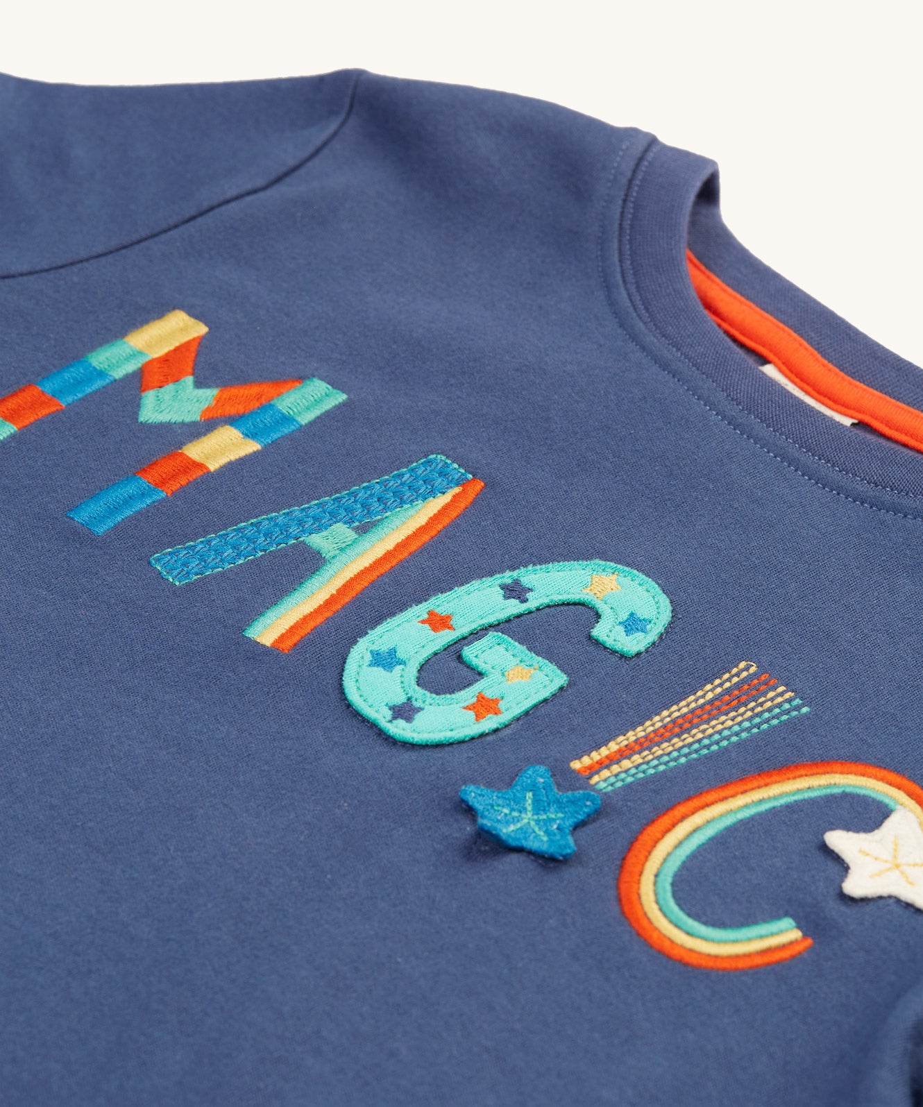 A closer look at the colourful, rainbow embroidered and applique magic lettering on the Frugi Adventure Applique Top - Navy Blue/Magic