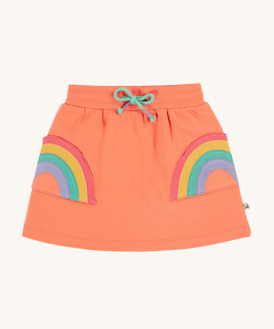 Frugi Sybil Skirt - Cantaloupe/Rainbow. A beautiful cantaloupe/coral fabric with large rainbow applique pockets, an elasticated waistband and a teal drawcord in the waistband