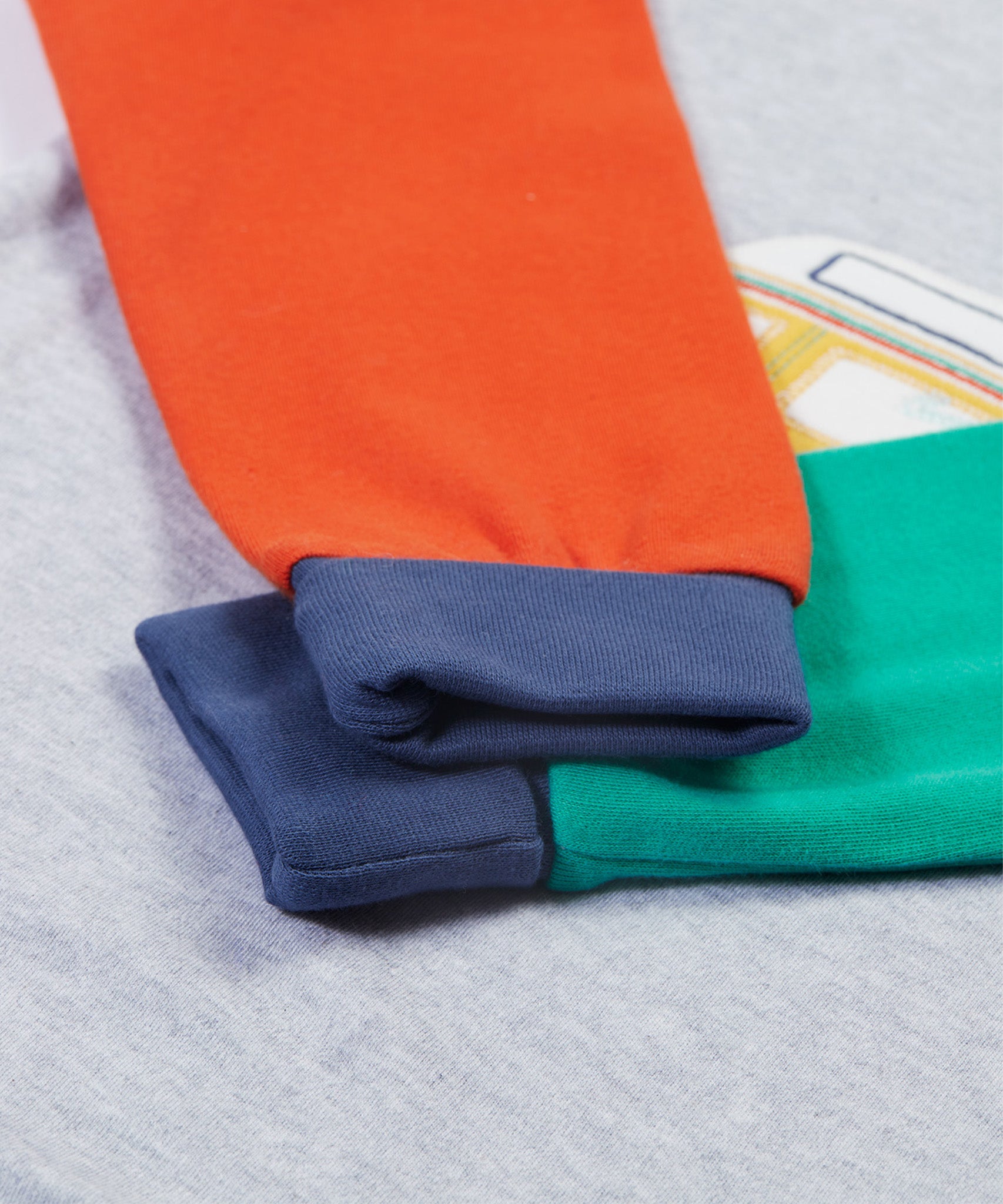 The colour block sleeves and cuffs in orange, green and navy, on the Frugi Jamie Jim Jams - Iguana Stripe/Camper