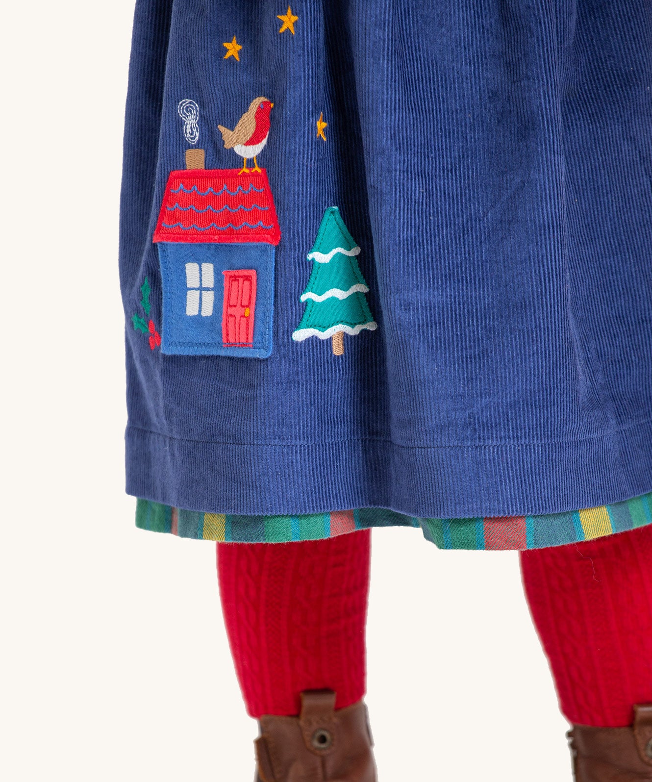 The bottom of the navy blue corduroy side of the Frugi Inara Cord Reversible Dress - Navy Blue/Rainbow Check, showing the applique detail