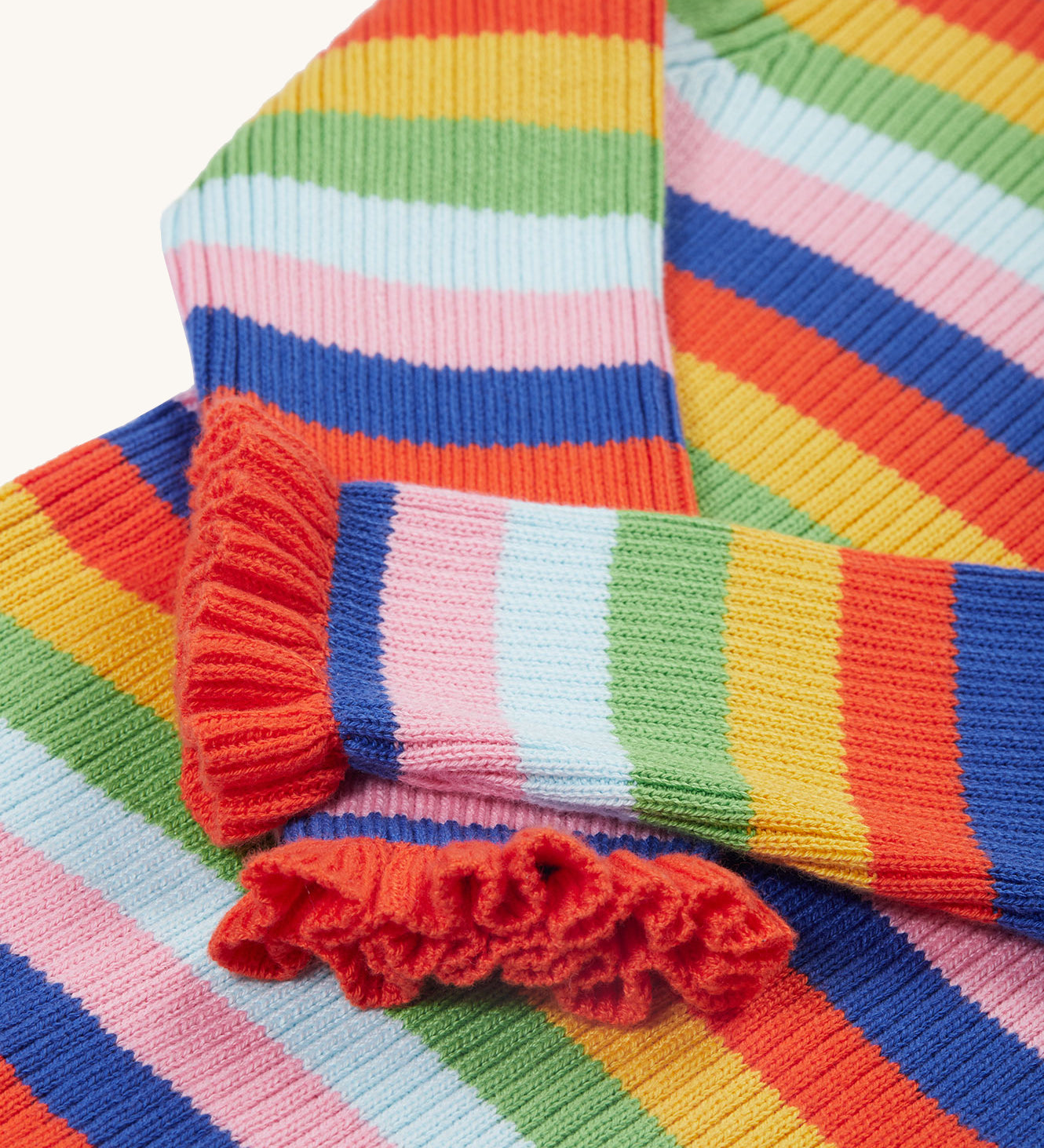 A closer look at the lovely ruffled wrist cuffs on the Frugi Zoe Knitted Jumper - Retro Stripe. The image also shows the bright and bold colour-block fabric