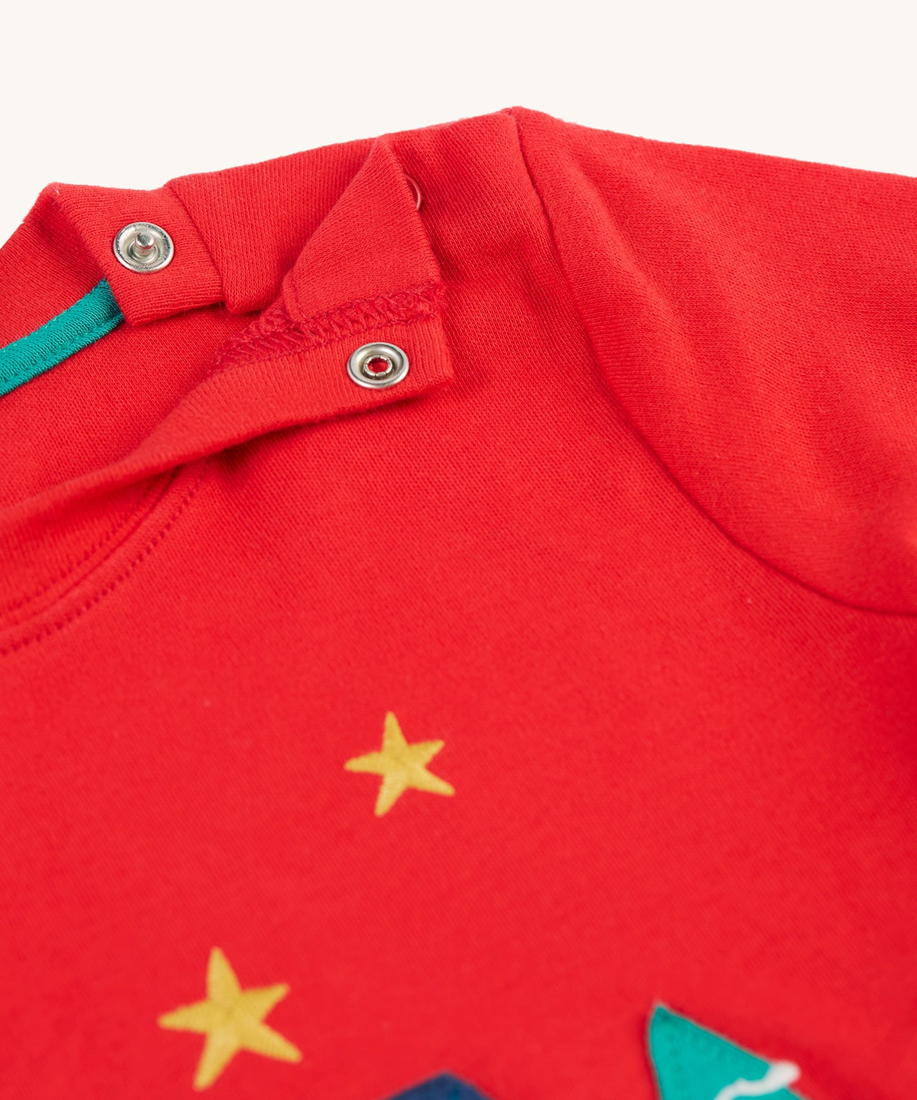 The popper fastenings on the shoulder of the Frugi Ira Interactive Applique Top - True Red/Winter Cottage