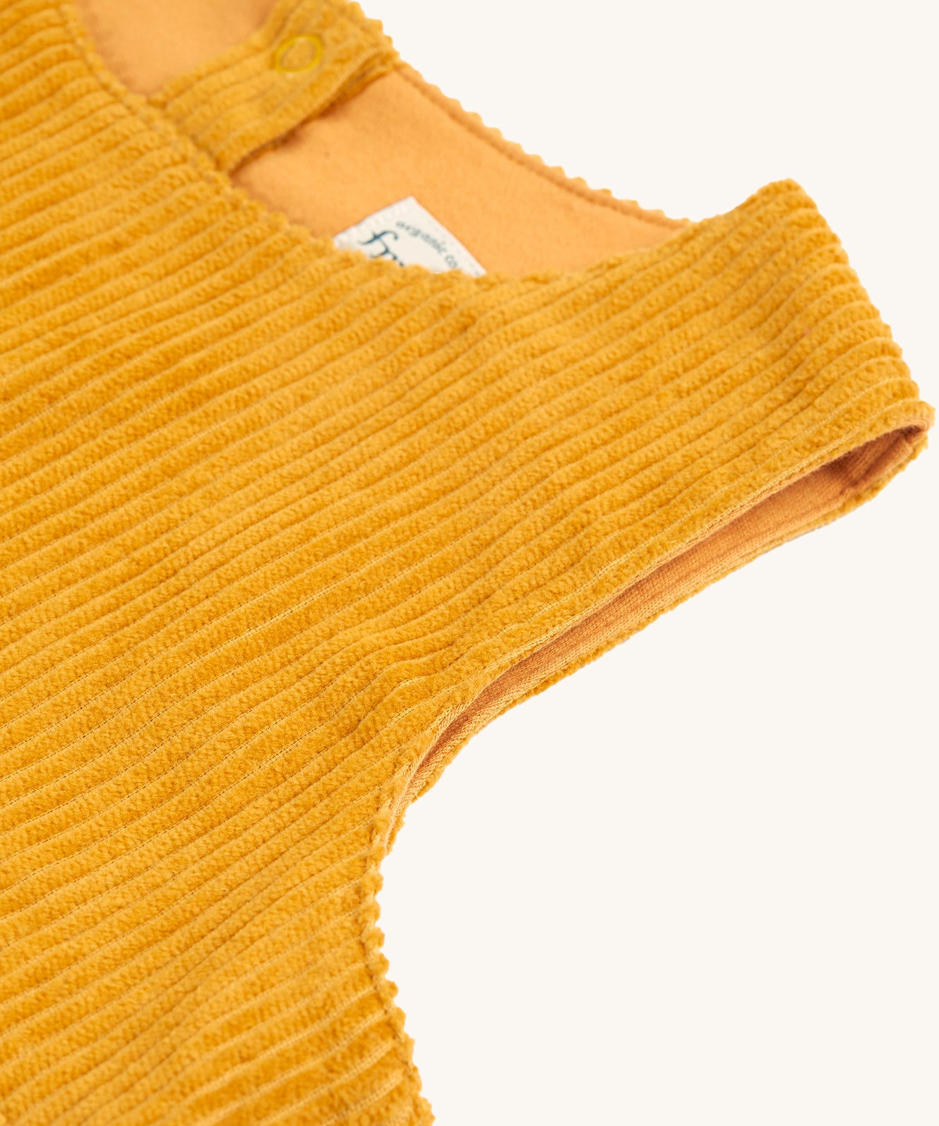 A closer look a the yellow, corduroy material and sleeveless shoulders on the Frugi Lovely Lily Cord Dress - Gold/Red Panda