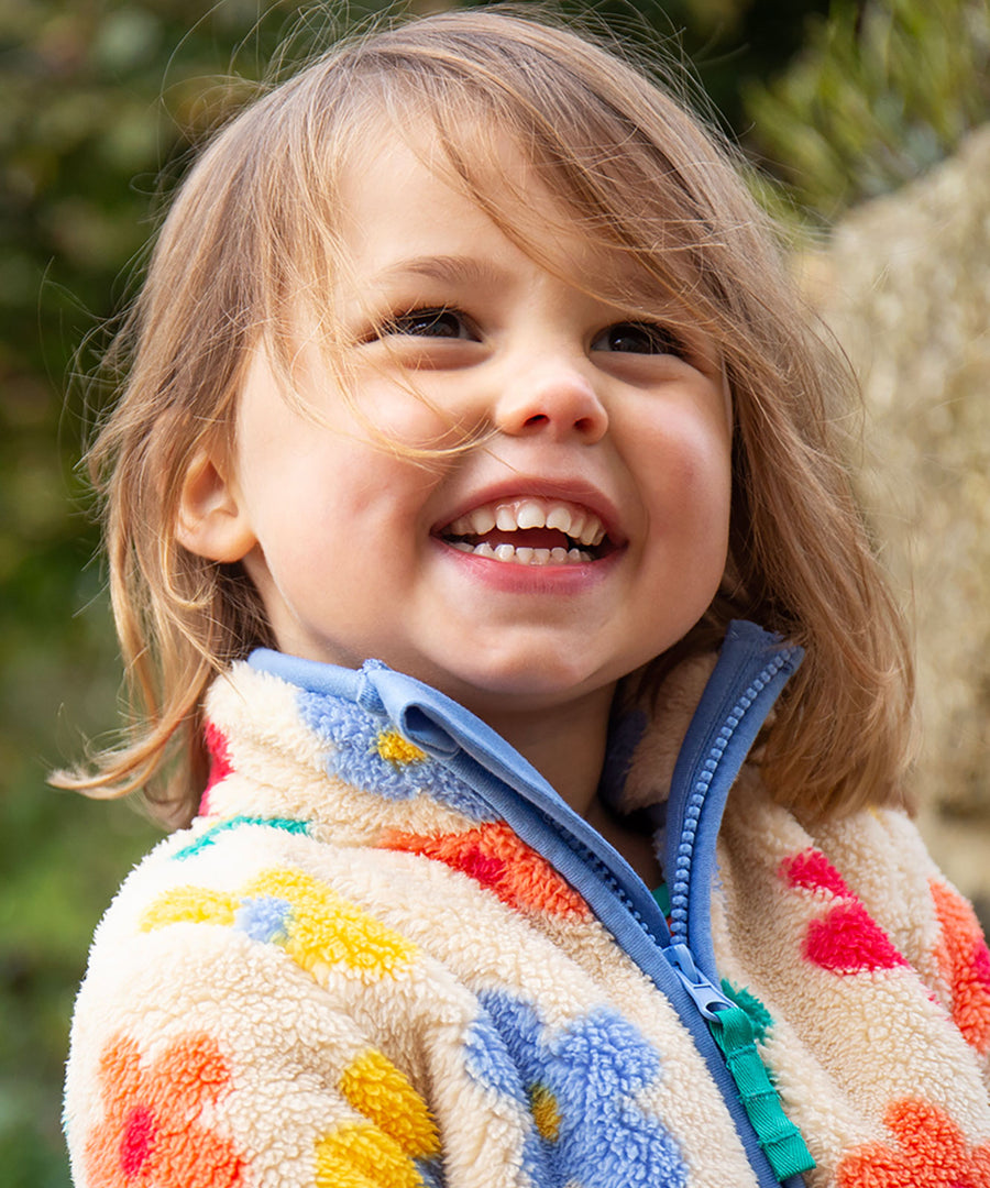 A child wearing the Frugi Zipped Ted Fleece Jacket - Flower Pop, showing the zipper open at the neck