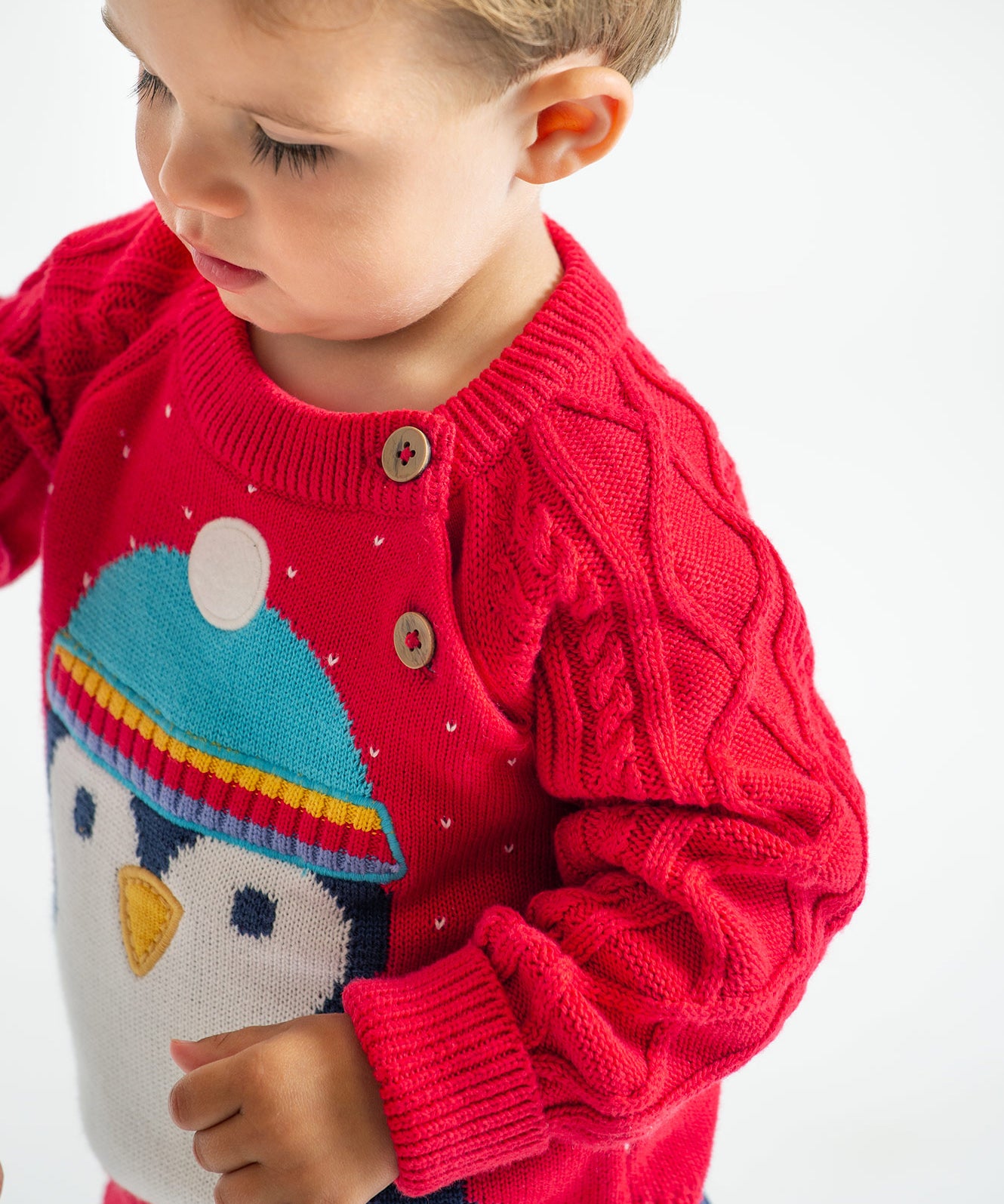 A closer look at the shoulder buttons and cable knit sleeves on the Caleb Character Knit Jumper - True Red/Penguin