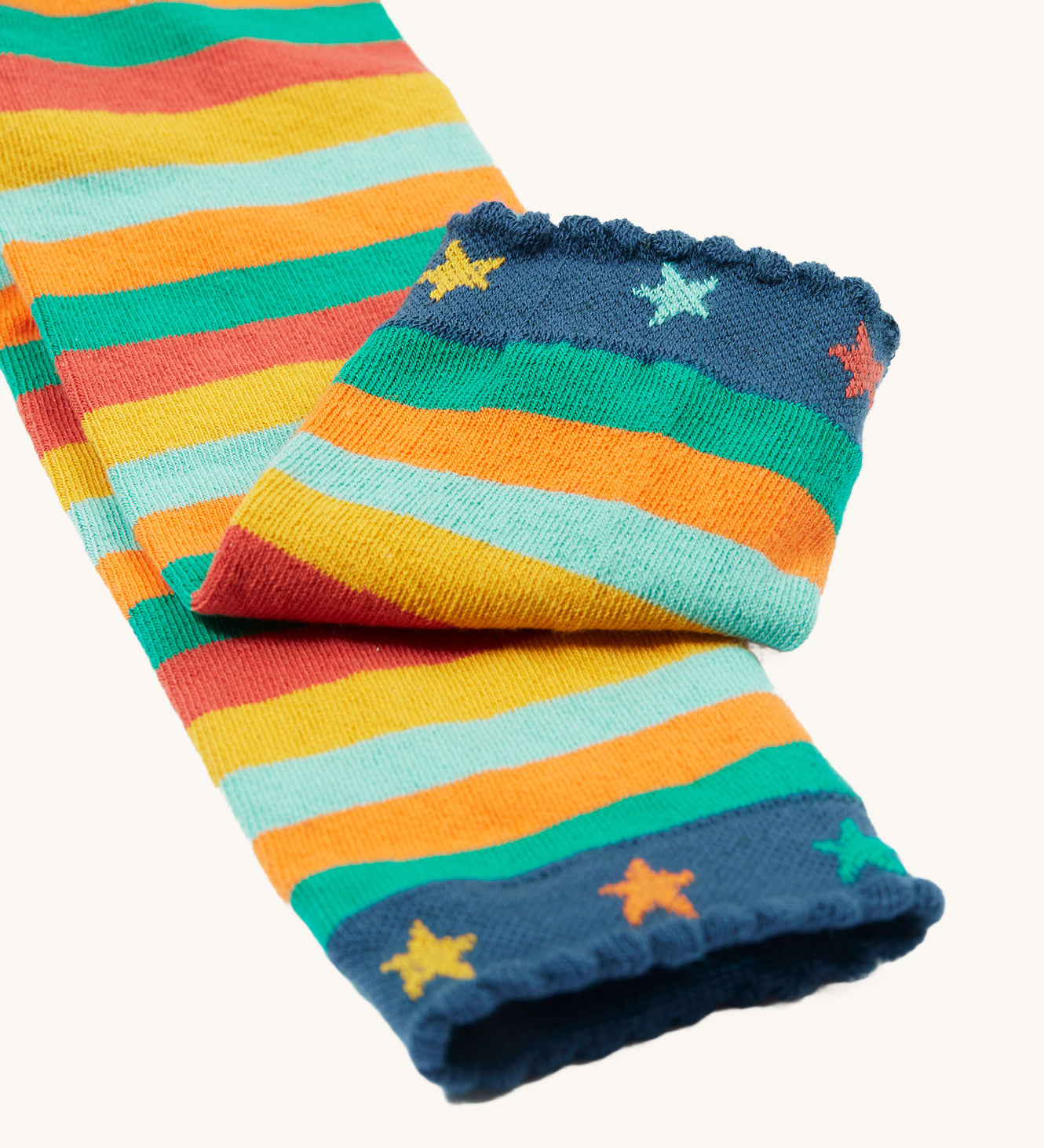 A closer look at the angle cuffs on teh Frugi Little Knitted Leggings - Rainbow Stripe/Tractor, with colourful stars and striped legs