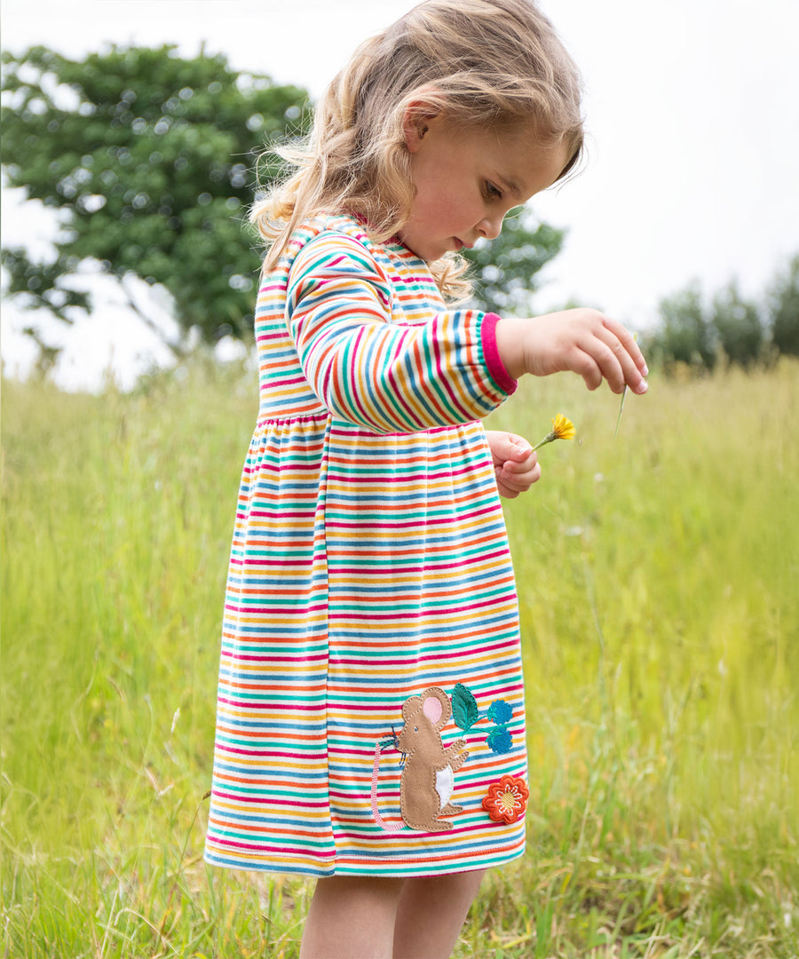 A child outside wearing the Frugi Dolcie Dress - Lingonberry Multi-Stripe