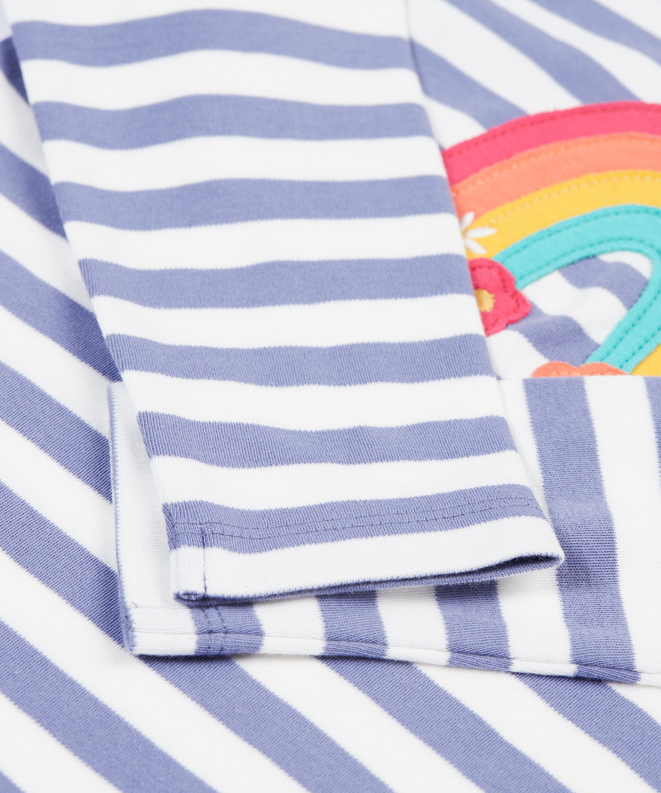 A closer look at the sleeves of the Frugi Louise Applique Top - Grape Stripe/Rainbow. The image shows soft, lilac and white striped sleeves with the rainbow applique poking out behind.