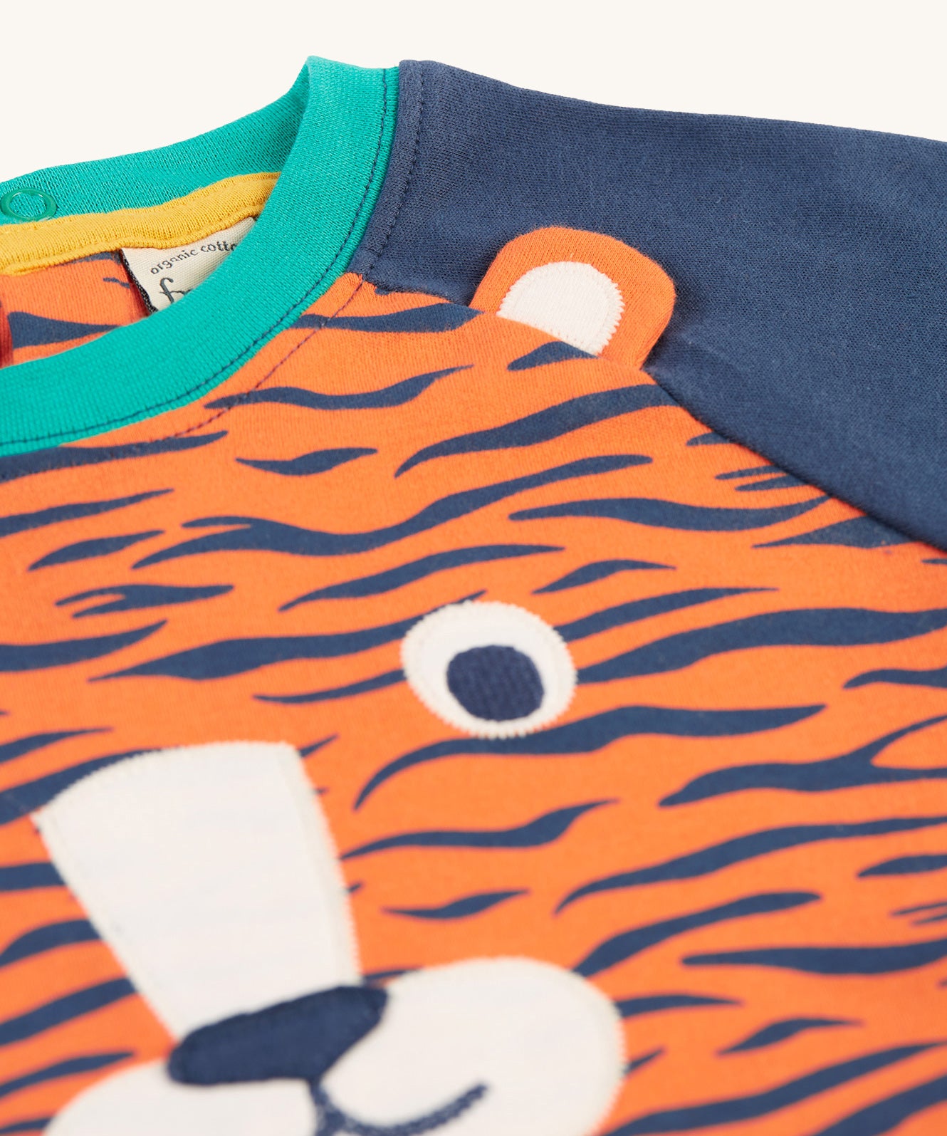 A closer lookat the interactive tiger ear on the Frugi Happy Raglan Top - Tiger