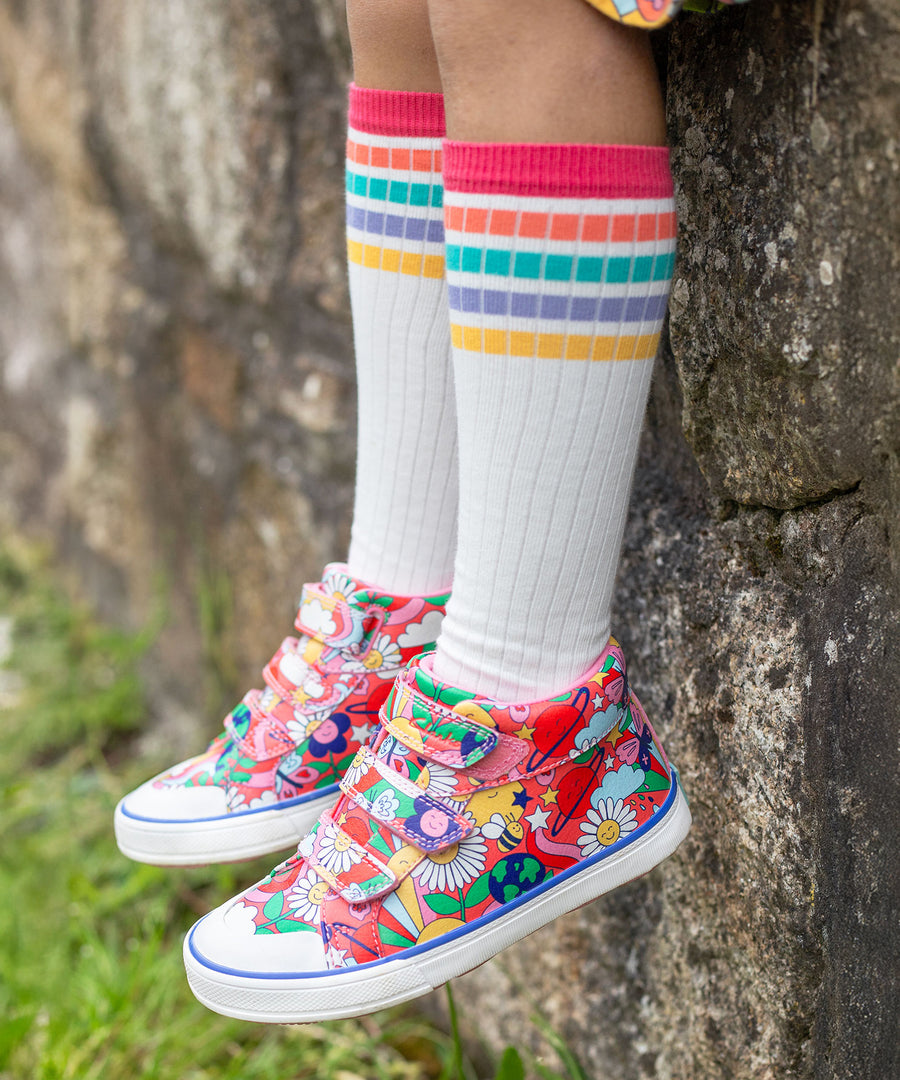 A child wearing Frugi trainers, and the Frugi Hygge Rib Knee Socks - Soft White Rainbow