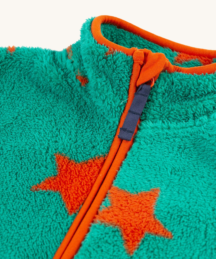 A closer look at the zipper on the Frugi Zipped Ted Fleece Jacket - Bonfire Stars, emphaising the orange piping and orange stars on the green fleece