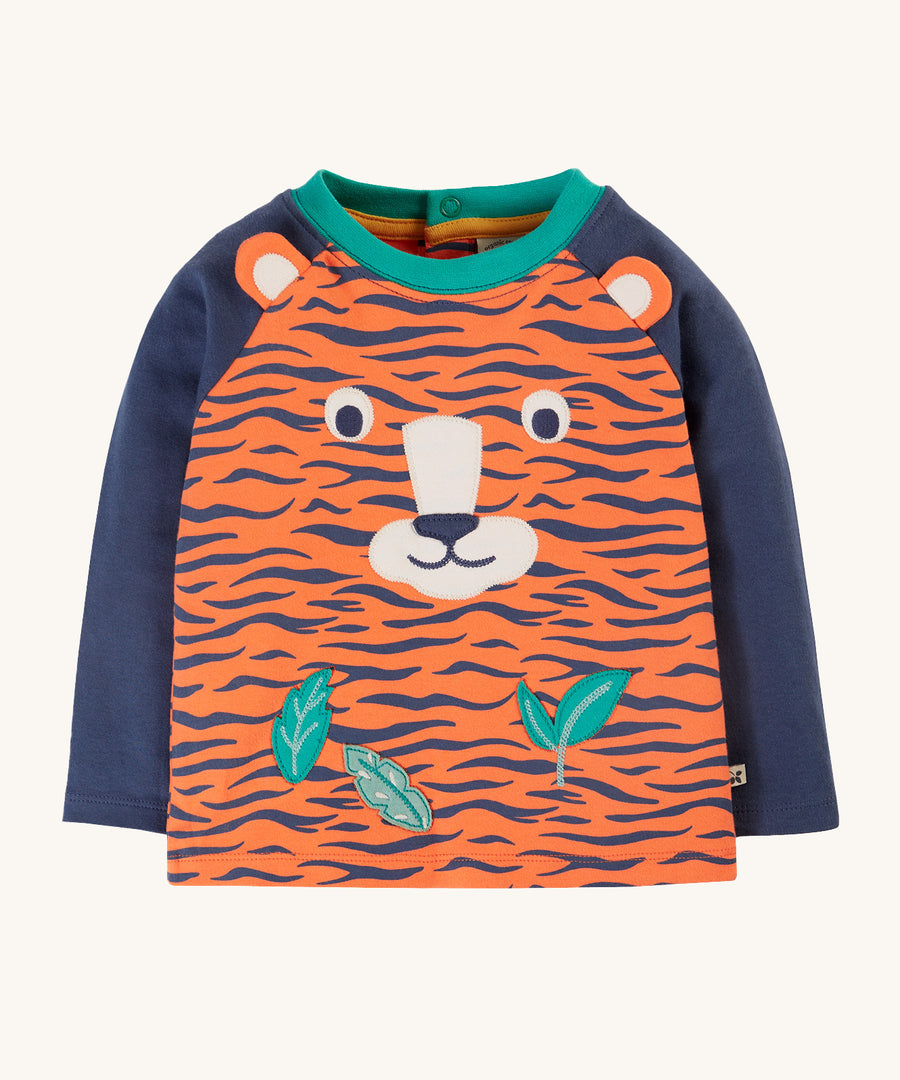 Frugi Happy Raglan Top - Tiger, with navy arms an orange and navy tiger stripe body and a fun tiger face and leaf applique on the front