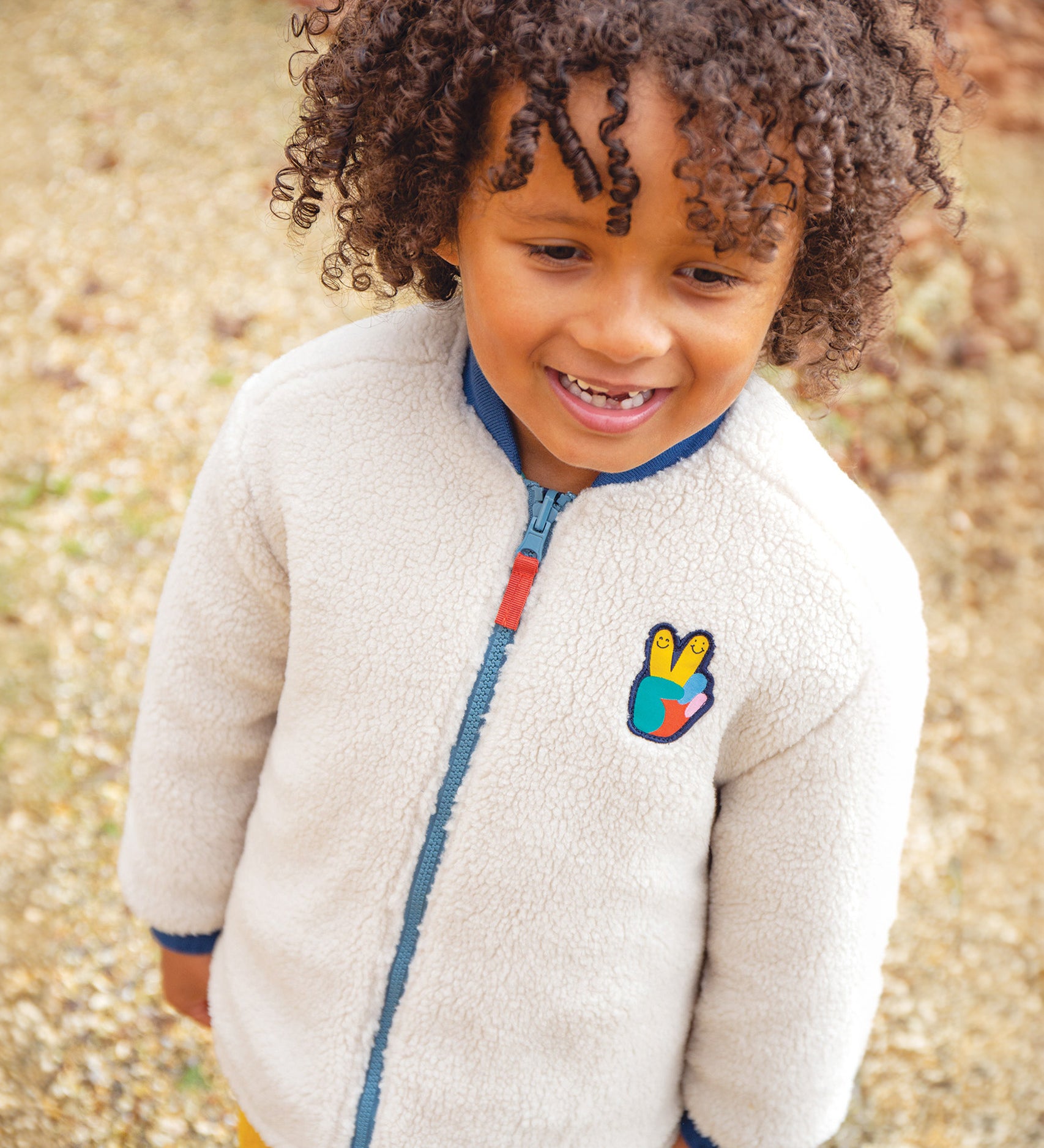 A chiled wearing the fleece side of the Frugi Robin Reversible Quilted Jacket - Teal/Moon