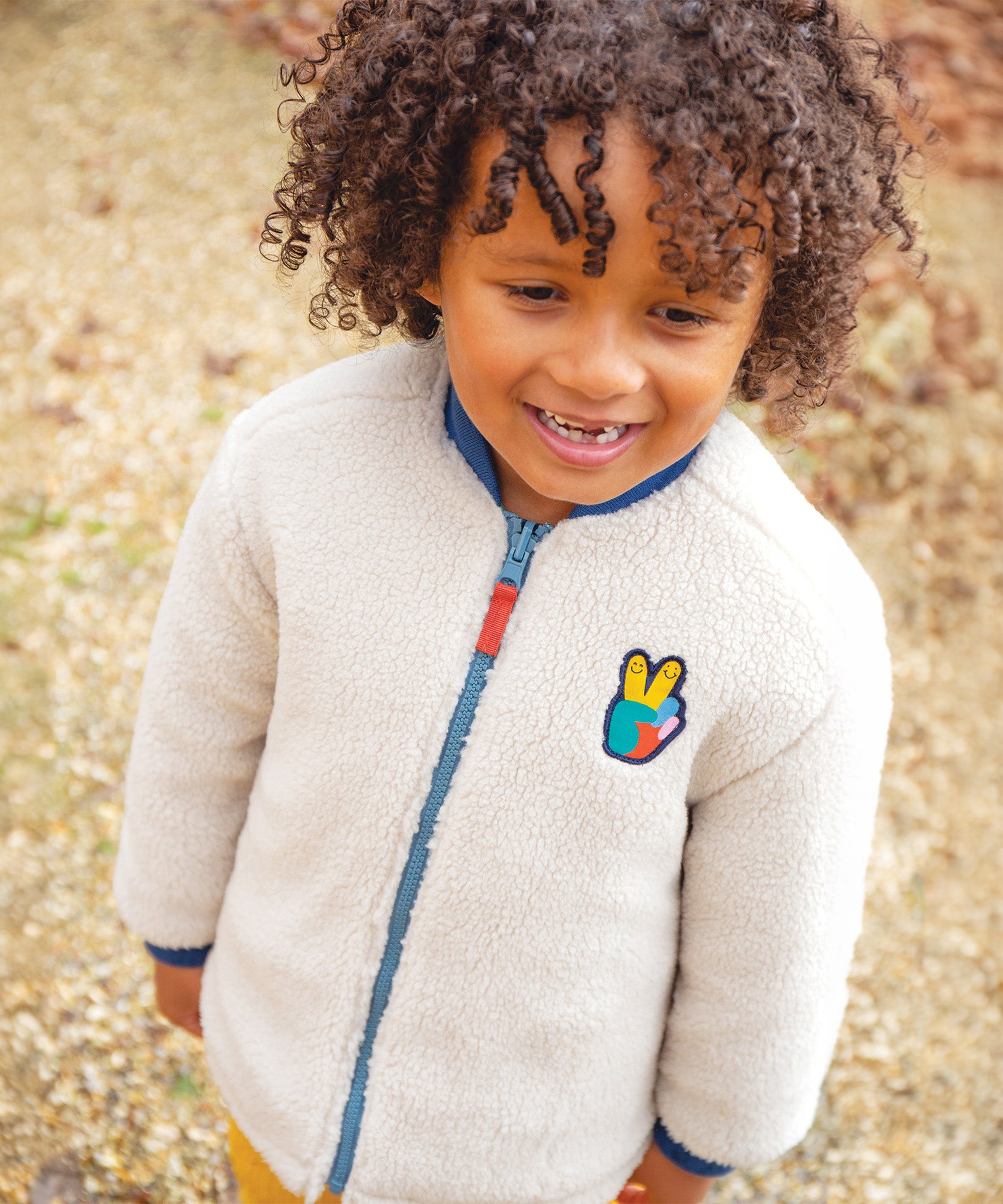 A chiled wearing the fleece side of the Frugi Robin Reversible Quilted Jacket - Teal/Moon