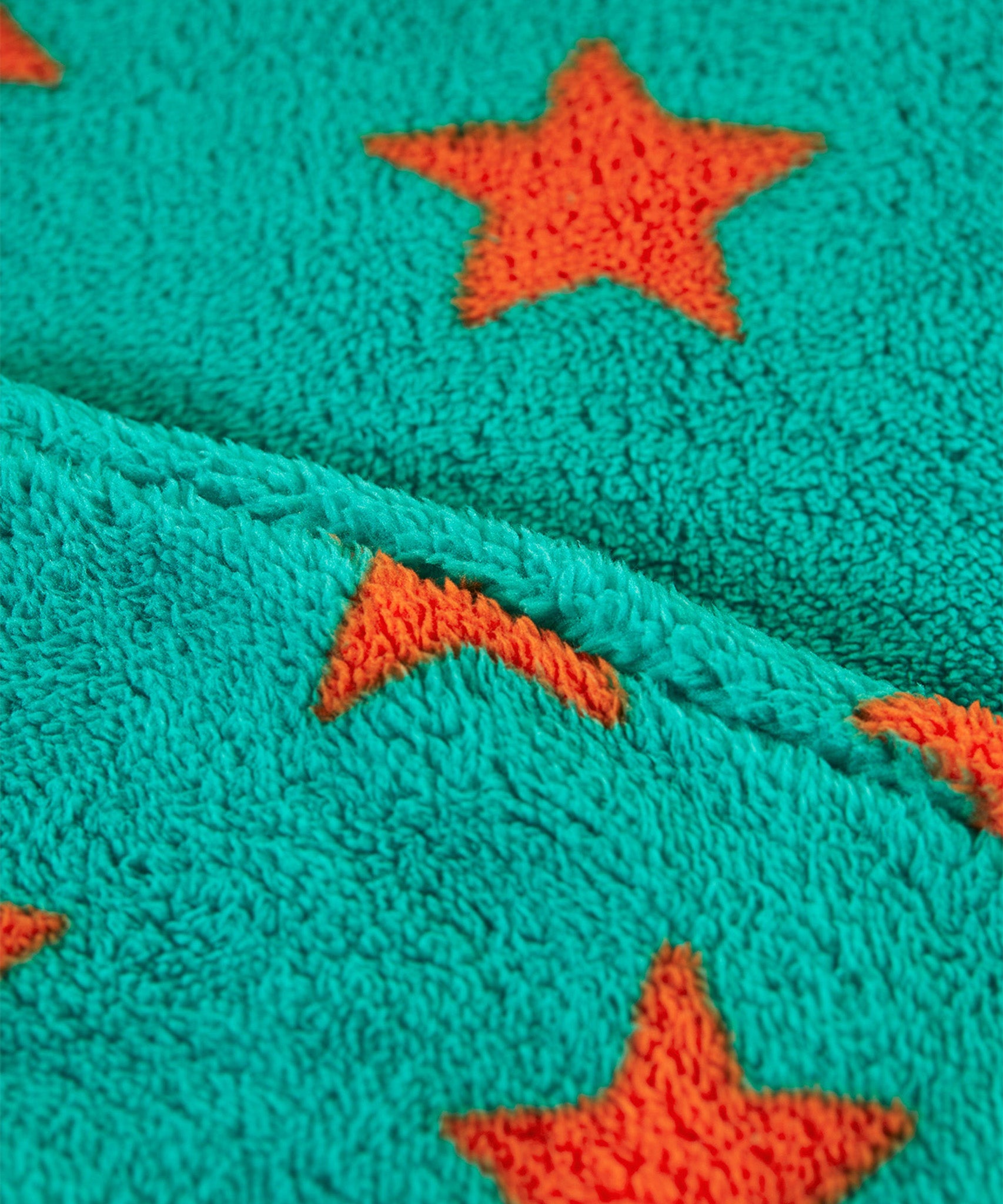 A closer look at the green fleece and orange stars on the Frugi Cosy Ted Snuggle Suit - Bonfire Stars