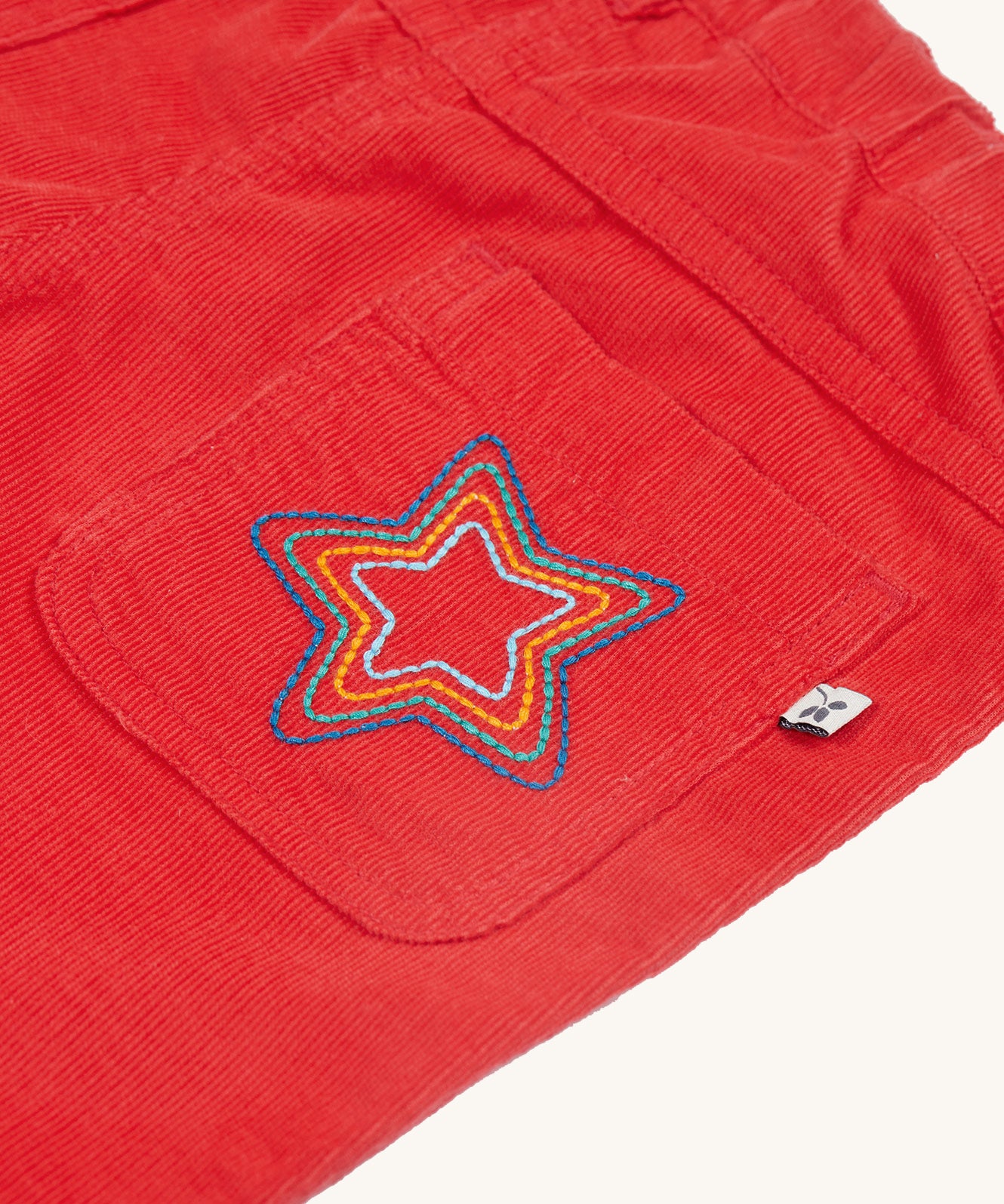 A closer look at the embroidered star on the back pocket of the Frugi Clover Slim Cord Trousers - True Red