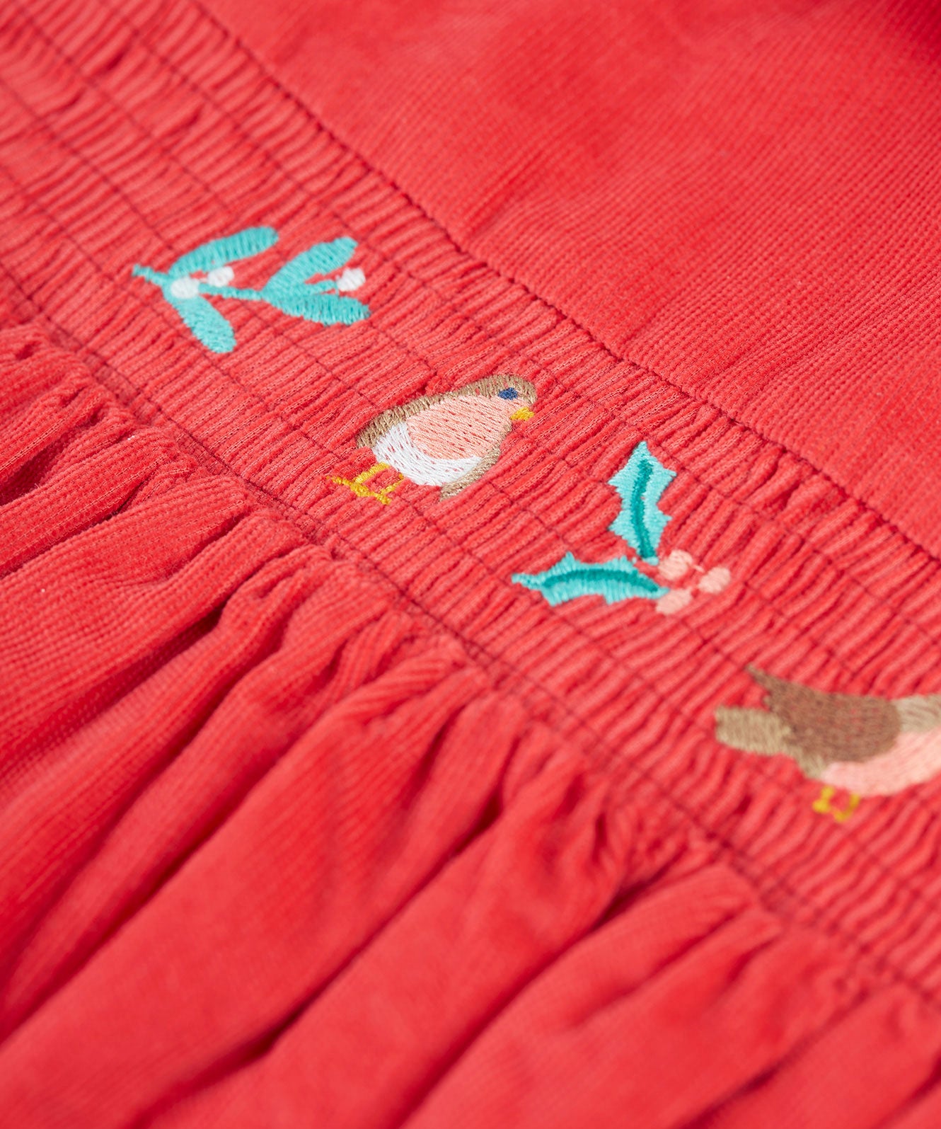 A closer look at the robin, holly leaf and mistletoe embroidery on the front of the Frugi Amilie Party Dress - True Red/Robin