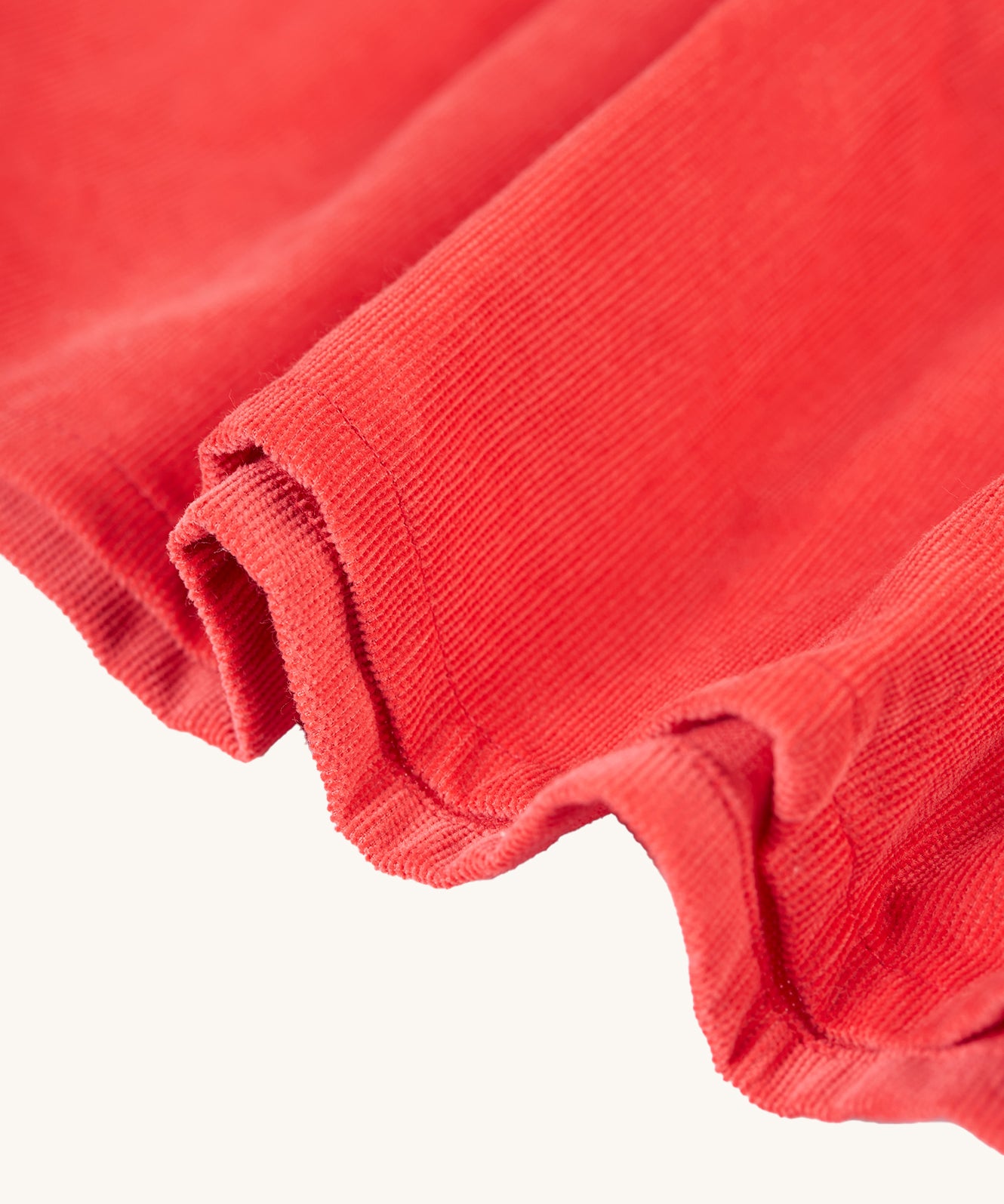 The red corduroy material texture up close from the Frugi Amilie Party Dress - True Red/Robin