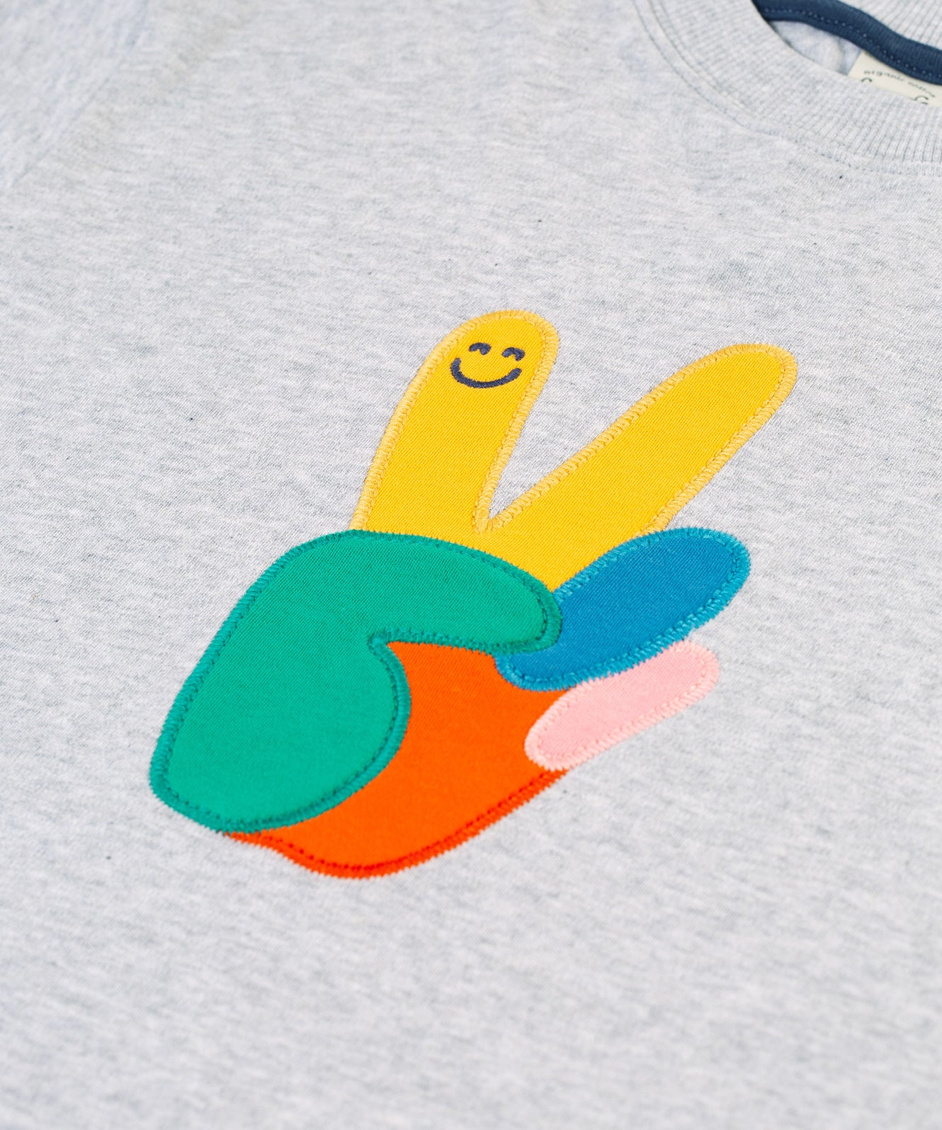 A closer look at the peace applique on the front of the Frugi Owen Top - Grey Marl/Peace