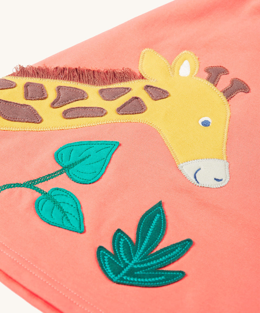 A closer look at the giraffe and leaf applique on the Frugi Paige Pinafore Outfit - Cantaloupe/Iguana Breton