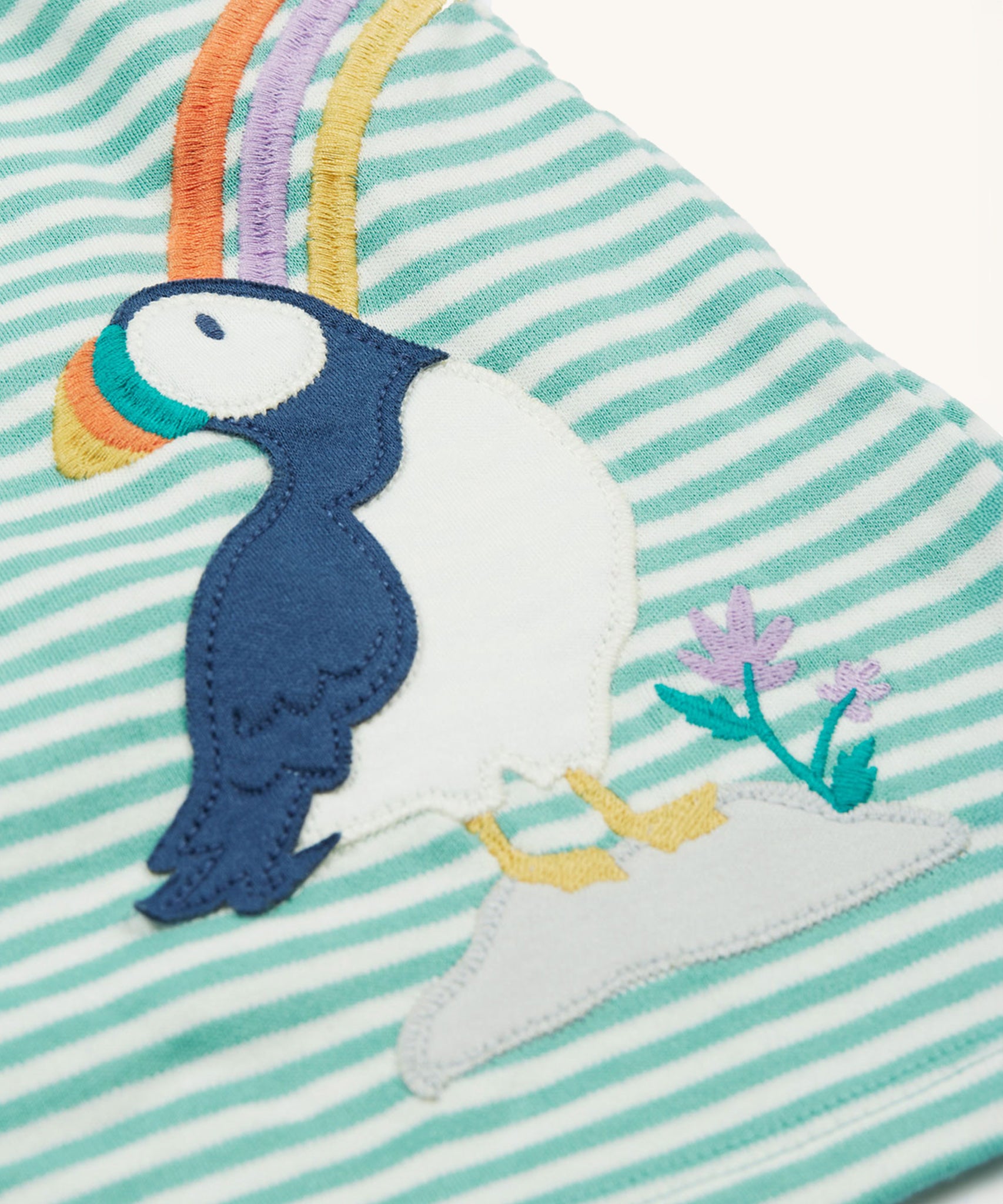 The Frugi Puffin applique on the Frugi Dolcie Dress - Moss Stripe/Puffin Rainbow