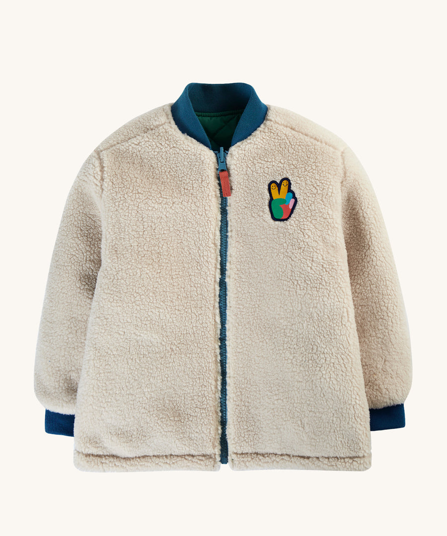 The fleece side of the Frugi Robin Reversible Quilted Jacket - Teal/Moon, with navy blue collar, zipper and wrist cuffs, and a Frugi peace patch on the chest