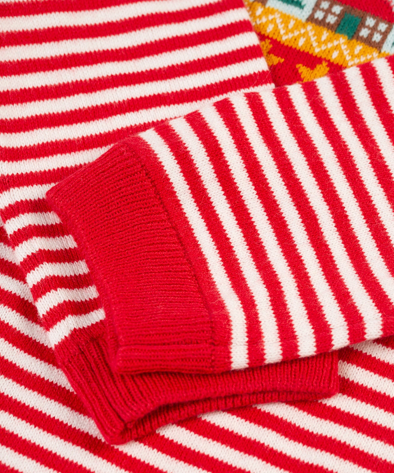 A closer look at the red and white stripe print on the sleeves of the Frugi Lumi Knitted Romper - Fairisle Christmas Stripe